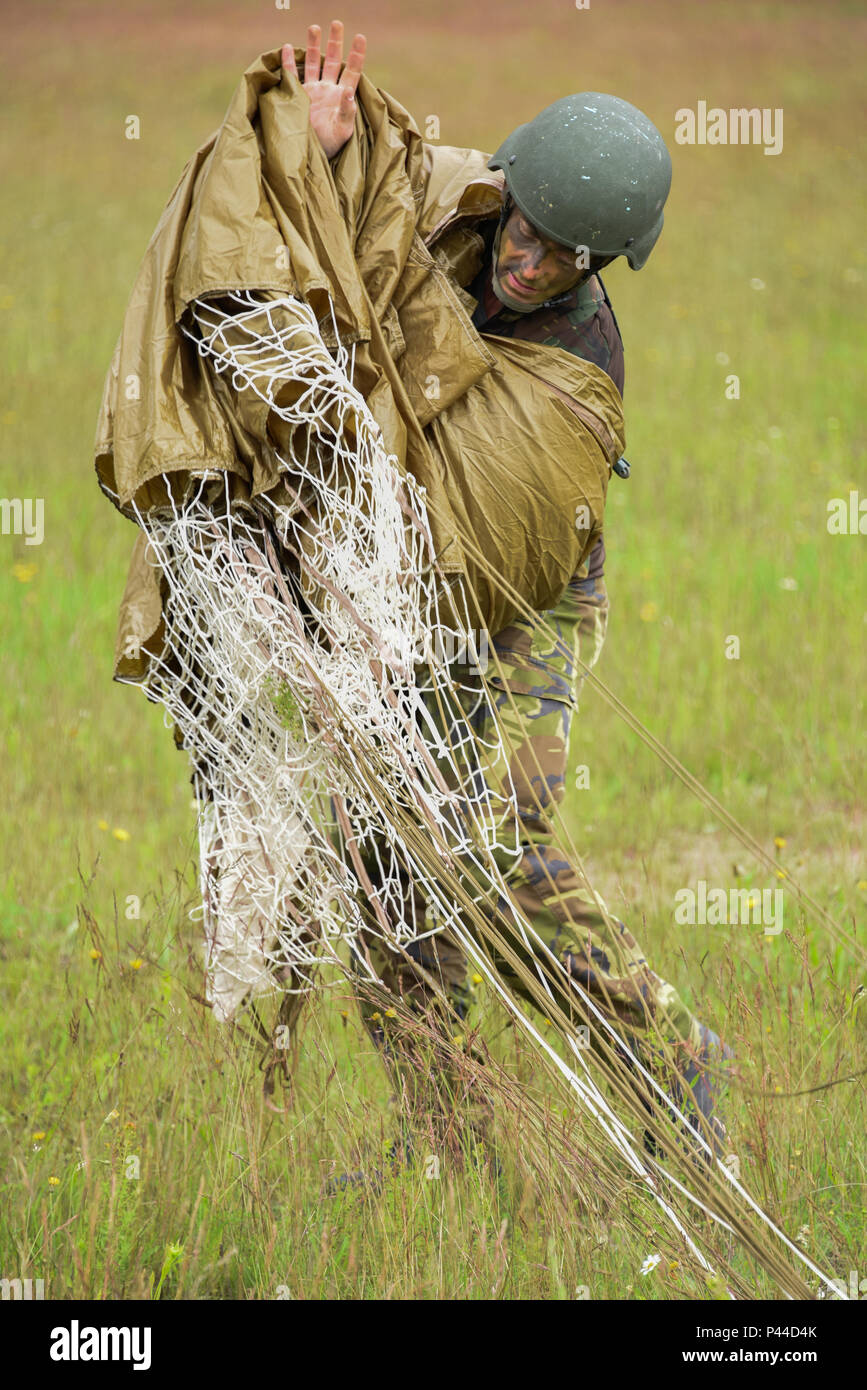 A Dutch Army paratrooper packs his parachute after jumping into Bunker Drop Zone at Grafenwoehr, Germany, June 15, 2016, during Exercise Swift Response 16.  Exercise Swift Response is one of the premier military crisis response training events for multi-national airborne forces in the world. The exercise is designed to enhance the readiness of the combat core of the U.S. Global Response Force - currently the 82nd Airborne Division's 1st Brigade Combat Team - to conduct rapid-response, joint-forcible entry and follow-on operations alongside Allied high-readiness forces in Europe. Swift Response Stock Photo