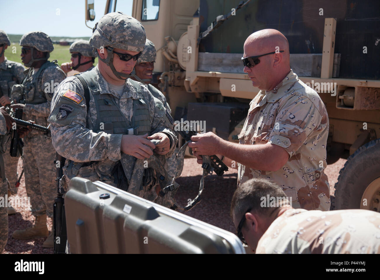 U.S. Army Staff Sgt. Michael Schwans of the 1st Battalion, 147th Field Artillery, South Dakota Army National Guard, hands a set of Multiple Integrated Laser Engagement System (MILES) Gear to Spc. Barry Gould of the 396th Medical Company (Ground Ambulance), Army Reserve, prior to a convoy operations exercise during the Golden Coyote exercise in Camo Guernsey, Wyo., June 15, 2016.  The Golden Coyote exercise is a three-phase, scenario-driven exercise conducted in the Black Hills of South Dakota and Wyoming, which enables commanders to focus on mission essential task requirements, warrior tasks a Stock Photo