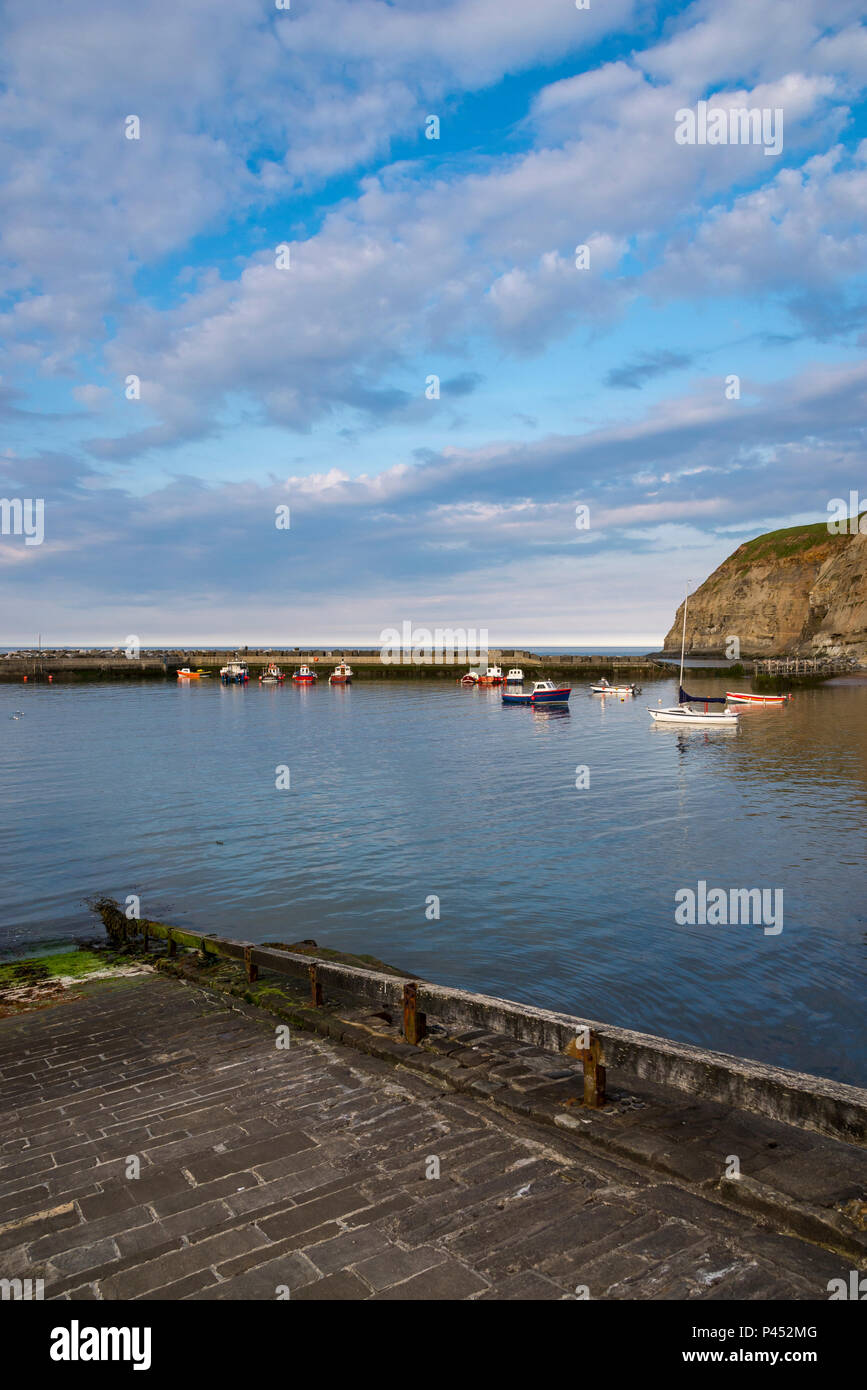 Small boats in the harbour at Staithes, North Yorkshire, North East England. A peaceful evening in May in this well known coastal village. Stock Photo