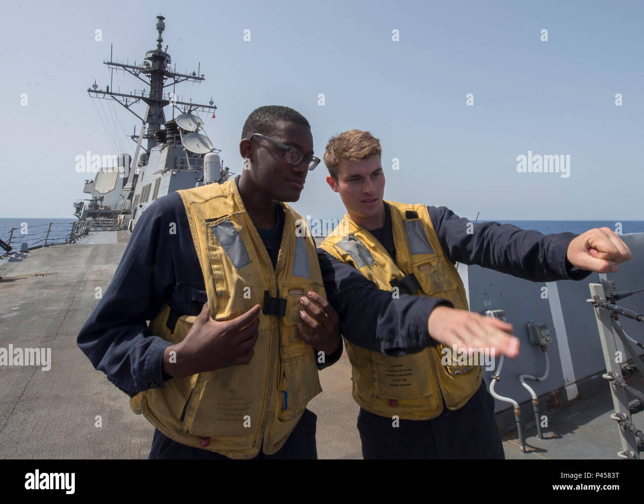 160612-N-AO823-069 RED SEA (June 12, 2016) Boatswain's Mate 2nd Class David Kostenbauder, right, trains Boatswain's Mate Seaman Jabri Singleton on landing signals before a helicopter in-flight refueling exercise aboard guided-missile destroyer USS Bulkeley (DDG 84). Bulkeley is deployed as part of the Harry S. Truman Carrier Strike Group in support of Operation Inherent Resolve, maritime security operations, and theater security cooperation efforts in the U.S. 5th Fleet area of operations. (U.S. Navy photo by Mass Communication Specialist 2nd Class Michael J. Lieberknecht/Released) Stock Photo