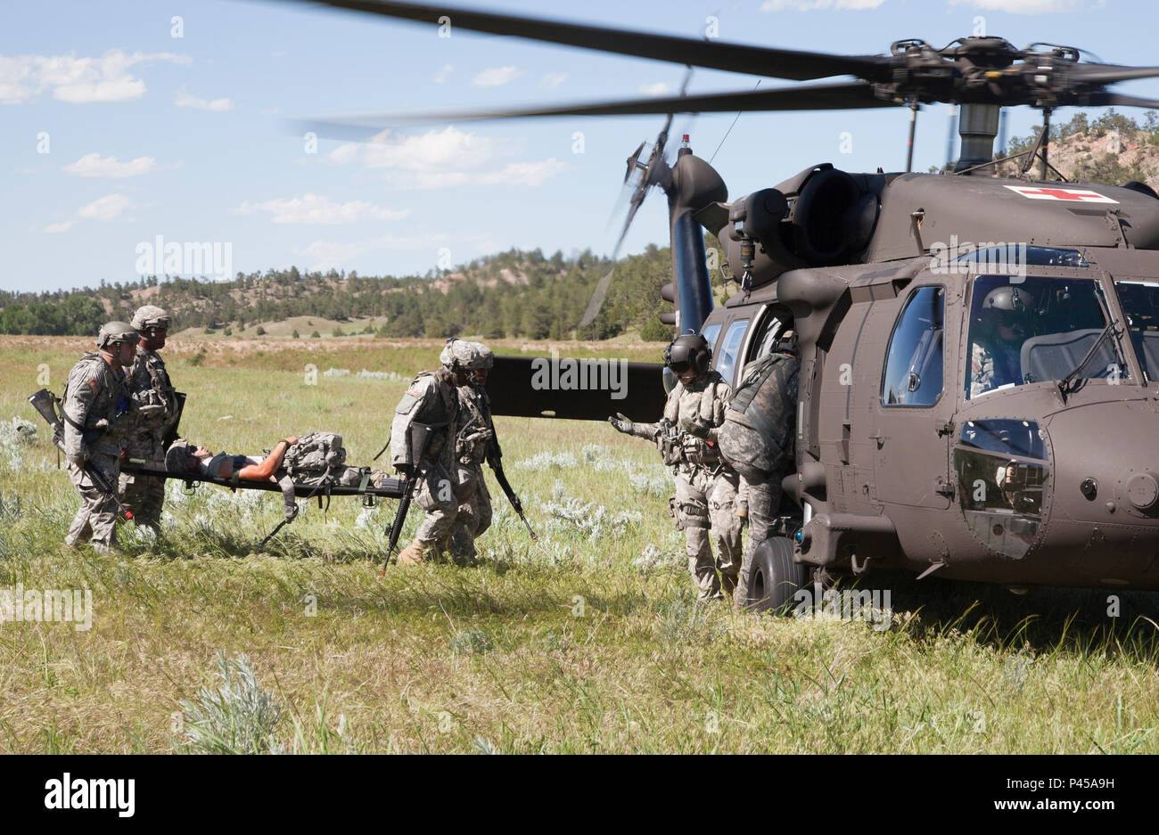 U.S. Army Soldiers of the 396th Medical Company (Ground Ambulance) and 235th Military Police Company, Army Reserve, load a simulated casualty onto a UH-60 Blackhawk during a convoy operations exercise Golden Coyote exercise in Camp Guernsey, Wyo., June 15, 2016. The Golden Coyote exercise is a three-phase, scenario-driven exercise conducted in the Black Hills of South Dakota and Wyoming, which enables commanders to focus on mission essential task requirements, warrior tasks and battle drills. (U.S. Army photo by Spc. Chenyang Liu/Released) Stock Photo