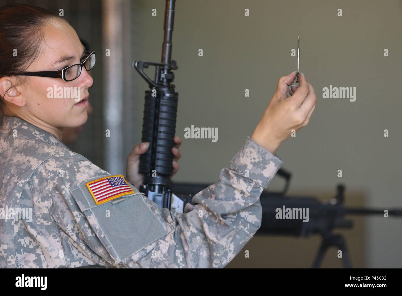 Arizona Army National Guard Sgt. Rachel H. Mick, a small-arms repairer with the 3666th Support Maintenance Company, inspects the firing pin on an M4 carbine, June 22, at Fort Greely, Alaska, which is located approximately 100 miles southeast of Fairbanks, Alaska. Mick was part of a mobile repair team from the Arizona Guard that inspected nearly 600 weapons for the Alaska National Guard’s 49th Missile Defense Battalion. (Arizona Army National Guard photo by Staff Sgt. Brian A. Barbour) Stock Photo