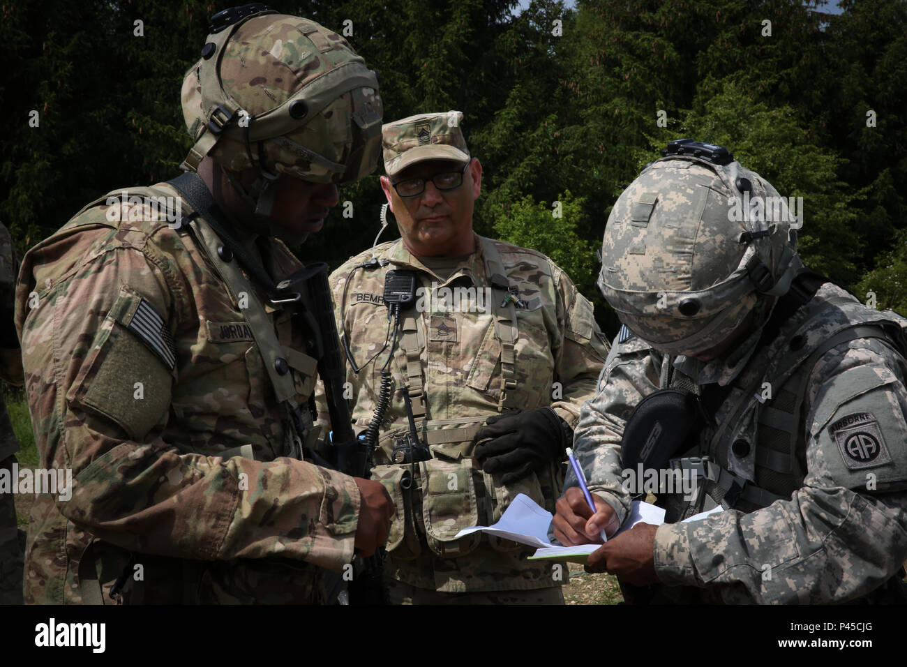 U.S. Army Sgt. 1st Class Robert R. Bemrose, center, of Joint Multinational Readiness Center (JMRC) (Operation Group) Adler Observer Coach Training monitors U.S. Soldiers of 1st Brigade Combat Team, 82nd Airborne Division discuss mission objective while conducting an AirLand operations to establish lodgement during Swift Response 16 training exercise at the Hohenfels Training Area, a part of the JMRC, in Hohenfels, Germany, Jun. 16, 2016. Exercise Swift Response is one of the premier military crisis response training events for multi-national airborne forces in the world. The exercise is design Stock Photo