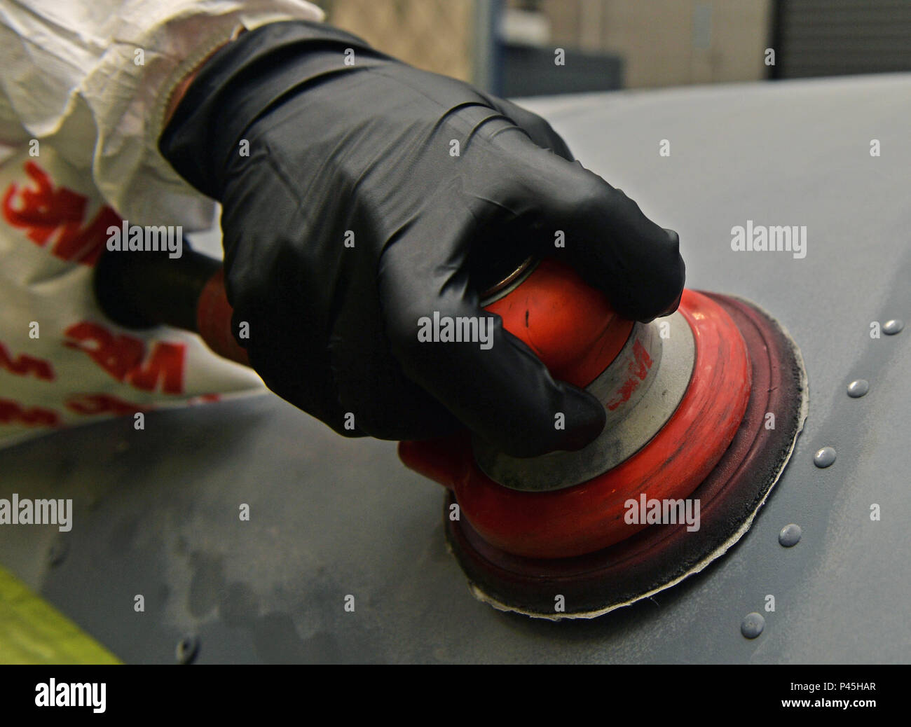 Airman Jay Adams, an aircraft structural maintenance journeyman with the 1st Special Operations Maintenance Squadron, sands an engine cowling at Hurlburt Field, Fla., June 29, 2016. During sanding, the old layer of paint is removed to create a better adhesive surface for the corrosion-preventing paint. (U.S. Air Force photo by Senior Airman Andrea Posey) Stock Photo