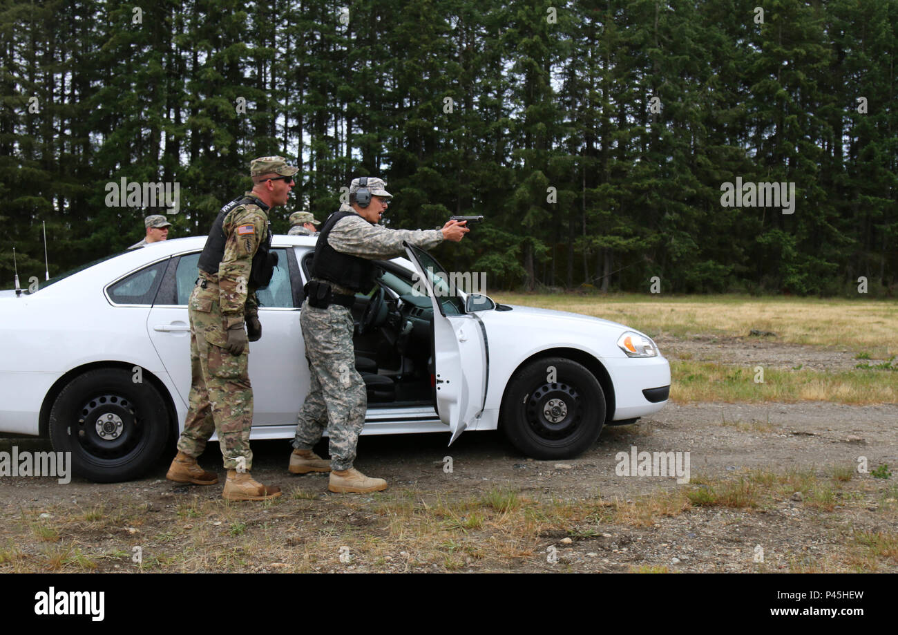 Staff Sgt. Jason Keller, military policeman with 42nd Military Police Brigade, observes and instructs a junior MP during a stress fire lane at Joint Base Lewis-McChord, Washington June 14, 2016. The stress fire training exercise took place as part of the Protector Professional Police Academy, a thirty day school MPs are required to complete in order to conduct street patrols and roadwork. Stock Photo