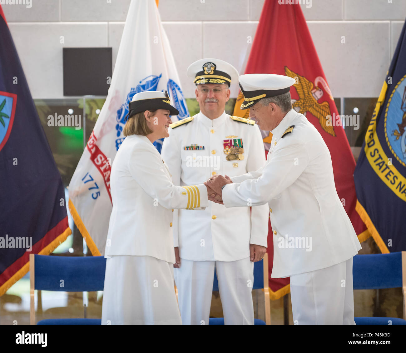 160630-N-QL030-271 NAVAL HOSPITAL GUAM - - Rear Adm. Bruce L. Gillingham (center), Commander Navy Medicine West, looks on as Capt. Jeannie Comlish (left) and Capt. Dan Cornwell (right) congratulate one another after formally changing command.  Cornwell relieved Comlish as commanding officer of U.S. Naval Hospital Guam in a change of command ceremony held at the main hospital in Agana Heights, Guam on June 30, 2016. (U.S. Navy photo by Hospital Corpsman 2nd Class Ryan Leverett/RELEASED) Stock Photo