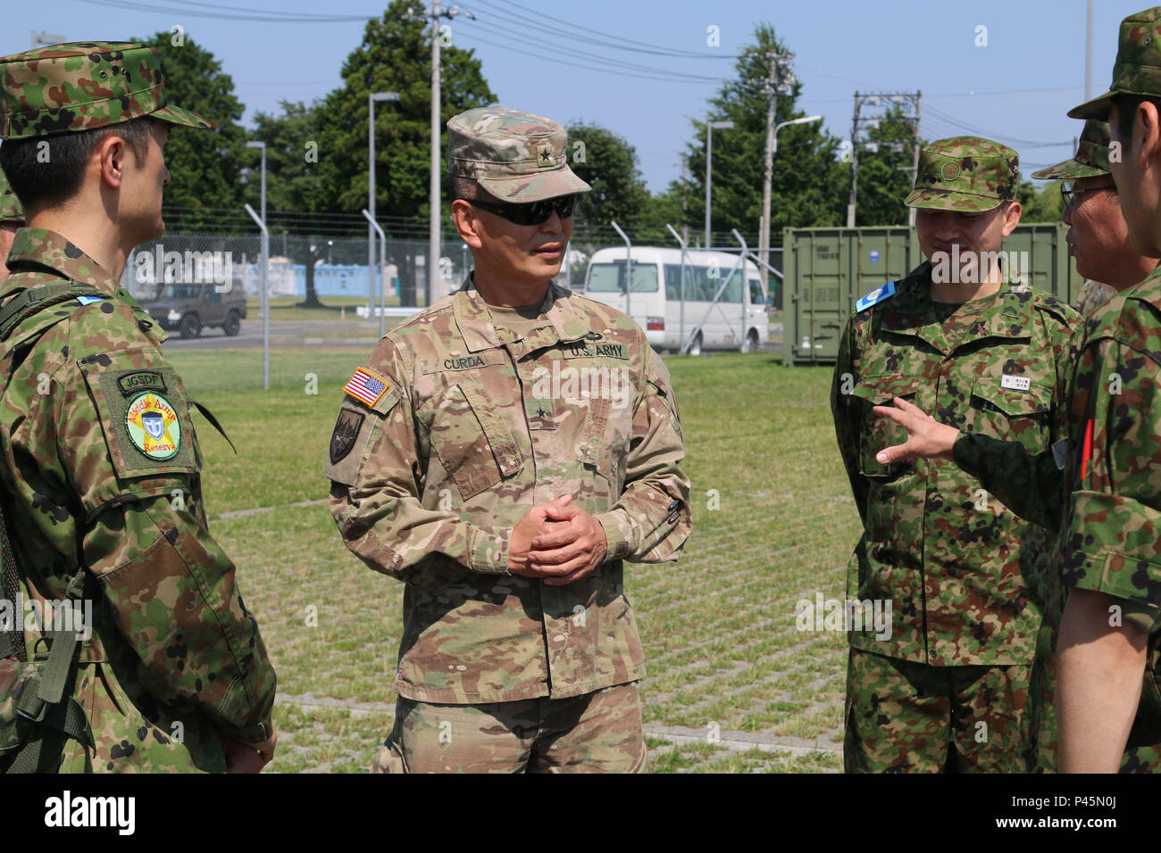 Brig. Gen. Stephen K. Curda (center), Commander, 9th Mission Support Command, visits with Japan Ground Self-Defense Force (JGSDF) service members at Sagamihara Depot Mission Training Complex during exercise Imua Dawn 2016, Sagamihara, Japan, June 18, 2016.  Imua Dawn 2016 provides opportunities for U.S. and Japanese forces to come together and train for potential real world events, better preparing them in supporting regional populations in all Humanitarian Assistance and Disaster Relief (HADR) and Noncombatant Evacuation Operations (NEO). Training together, the U.S. and Japan Ground Self-Defe Stock Photo