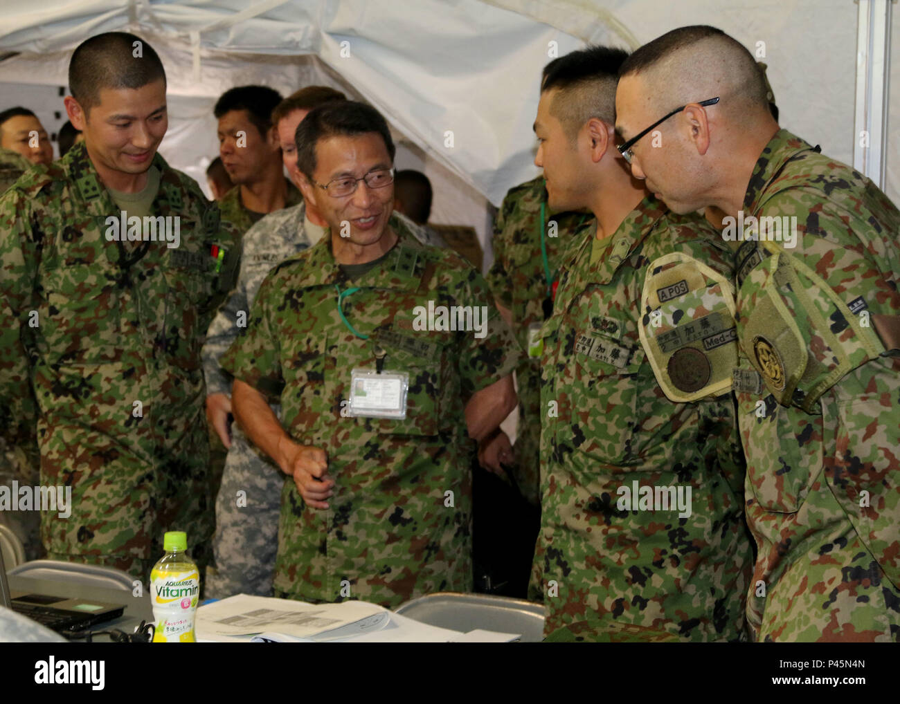 Maj. Gen. Mitsuhiko Horikiri, vice chief of staff (international), Japan Ground Self-Defense Force Central Readiness Force, visits with Japan Ground Self-Defense Force service members Cpt. Ikuo Igarashi (left), training officer, Sgt. Yuichi Kato, infantry man and Cpt. Yasuhiro Nakai, operations officer, during Imua Dawn 2016, Sagamihara Depot, Japan, June 18, 2016. Exercises such as Imua Dawn16 are fundamental training opportunities for military forces to refine techniques to rapidly respond to natural disasters and crises in order to help mitigate human suffering and greater property damage.  Stock Photo