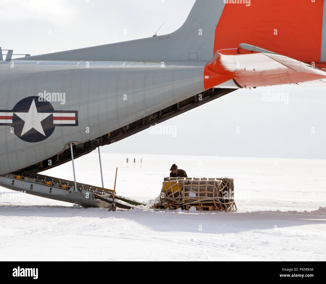 New York Air National Guard Staff Sgt. Matthew Jones, 109th Airlift Wing LC-130 'Skibird' Loadmaster clears snow from a pallet being uploaded onto a LC-130 'Skibird at Camp Raven, Greenland, on June 28, 2016.An LC-130 'Skibird' from the New York Air National Guard's 109th Airlift Wing in Scotia, New York, lands at Camp Raven, Greenland, near the DYE-2 site, on June 28, 2016. Crews with the 109th AW use Camp Raven as a training site for landing the ski-equipped LC-130s on snow and ice. Four LC-130s and  80 Airmen from the Wing recently completed the third rotation of the 2016 Greenland season. Stock Photo