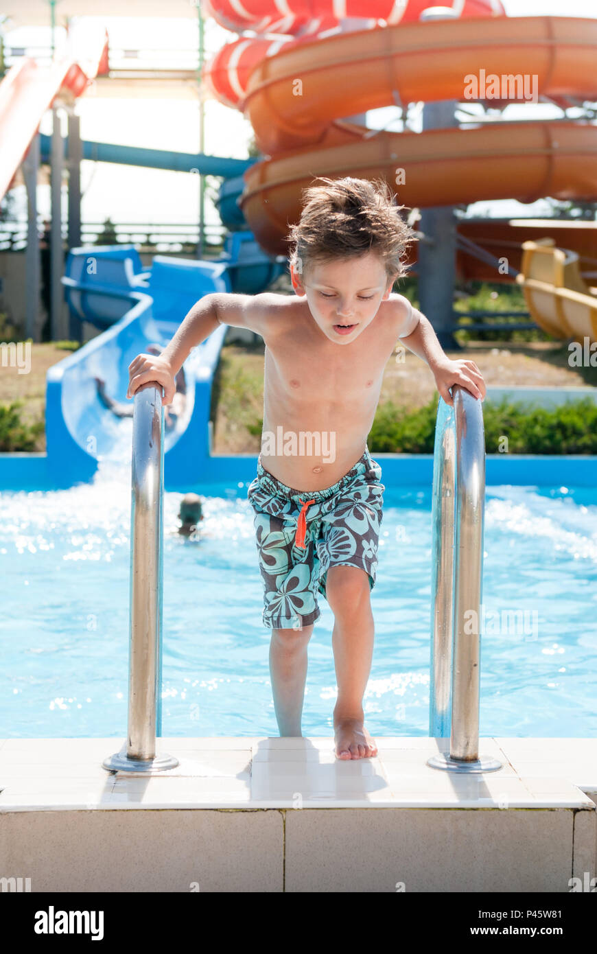 healthy little kid getting out of swimming pool in summer water park