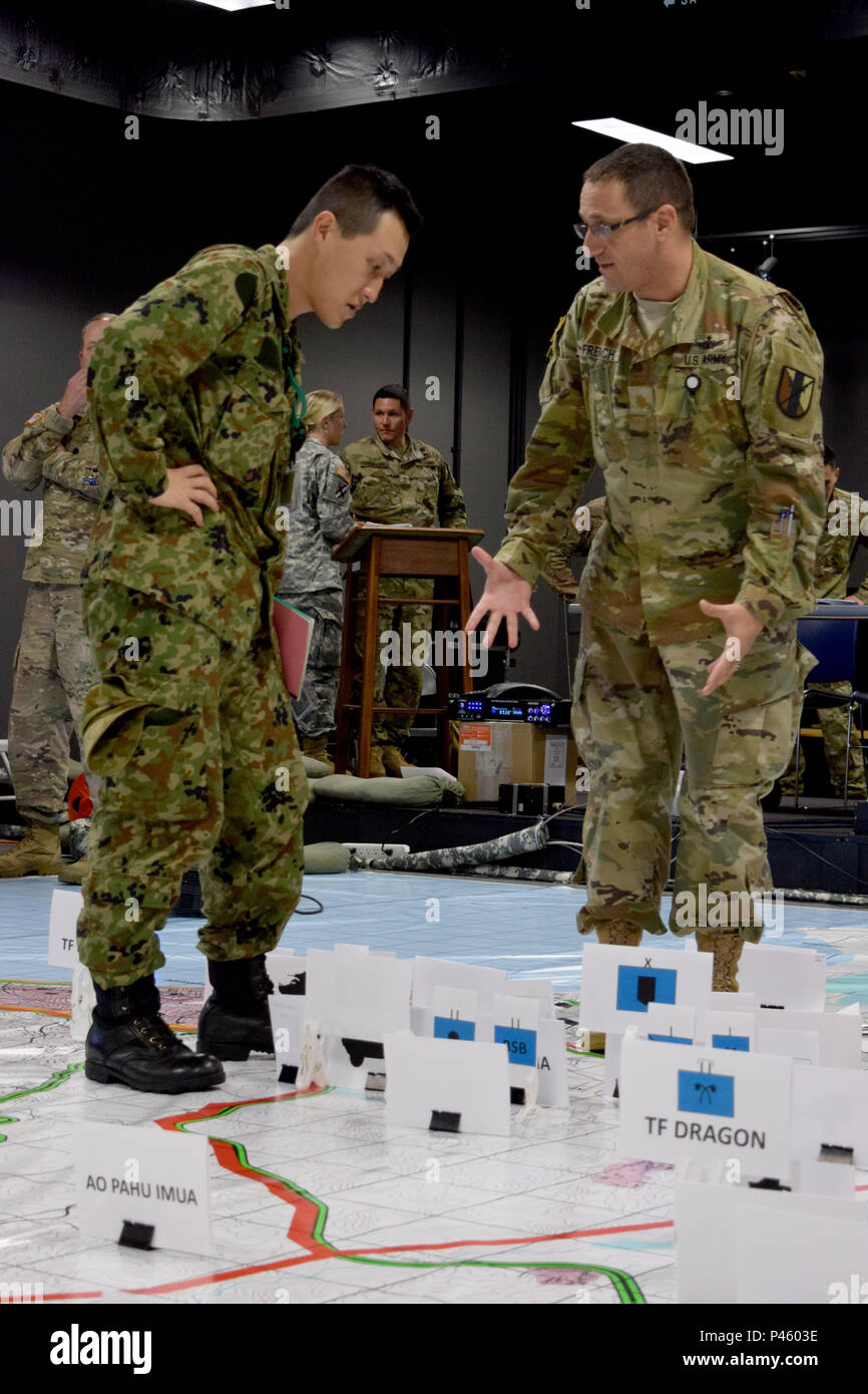 Japan Ground Self-Defense Force service member (left) and Maj. James French, operations and plans officer, 303rd Maneuver Enhancement Brigade, review the posture of unit assets and capabilities on a simulated battle field during the Combined Arms Rehearsal brief, Sagamihara Depot, Japan, June 15, 2016. Imua Dawn 2016 provides opportunities for U.S. and Japanese forces to come together and train for potential real world events, better preparing them in supporting regional populations in all Humanitarian Assistance and Disaster Relief (HADR) and Noncombatant Evacuation Operations (NEO). Stock Photo