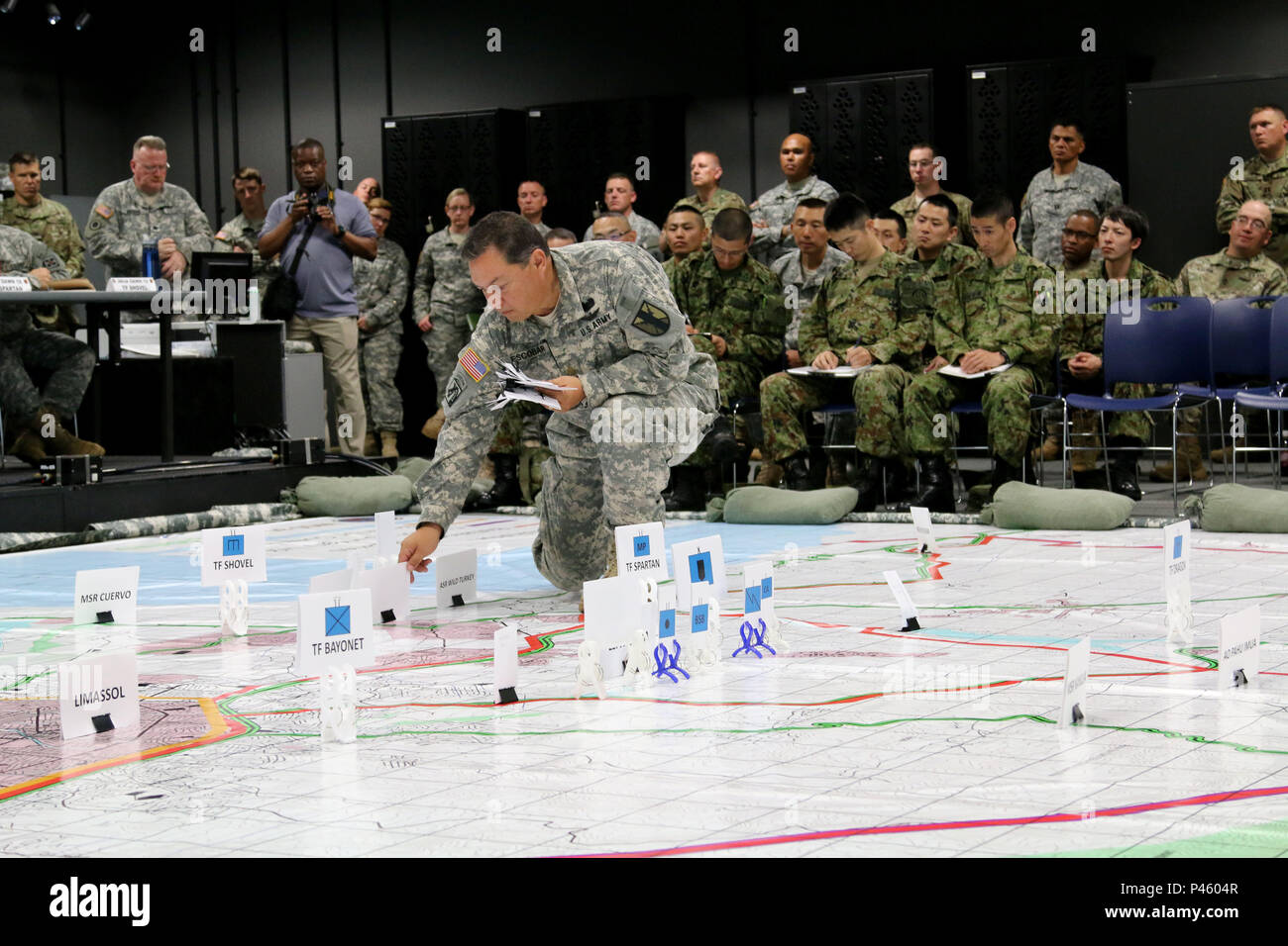 Maj. Timothy Escobar, staff judge advocate officer, 303rd Maneuver Enhancement Brigade, positions capabilities and asset targets on a simulated training map during exercise Imua Dawn 2016 Combined Arms Rehearsal brief, Sagamihara Depot, Japan, June 15, 2016. Exercises such as Imua Dawn 2016 are fundamental training opportunities for military forces to refine techniques to rapidly respond to natural disasters and crises in order to help mitigate human suffering and greater property damage. Without forward deployed forces, rapid and fully capable deployments to provide relief and safety followin Stock Photo