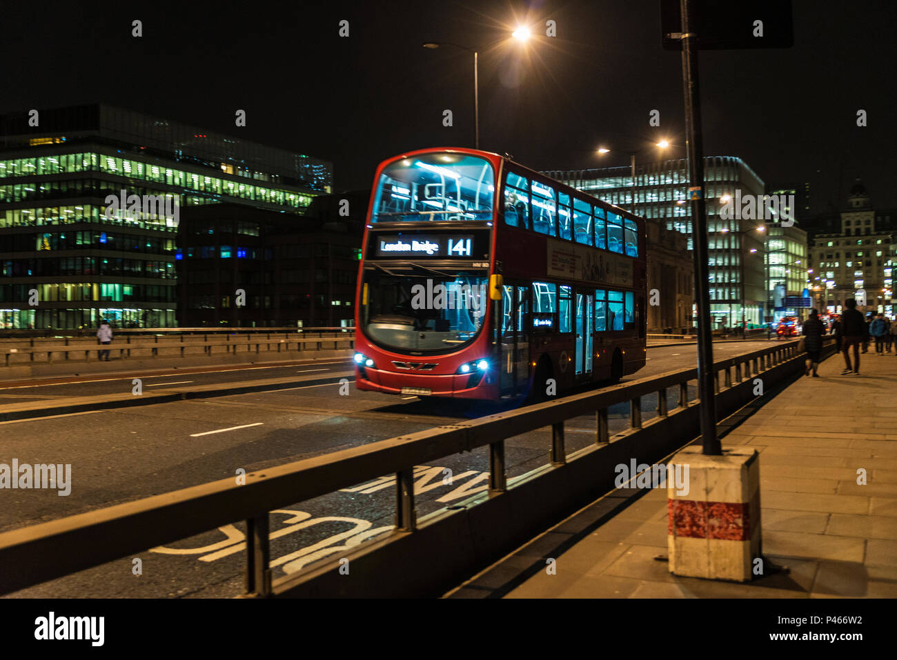 London, England UK  - December 30, 2018: Bus circulating on a bridge at night with people around in London, England UK Stock Photo