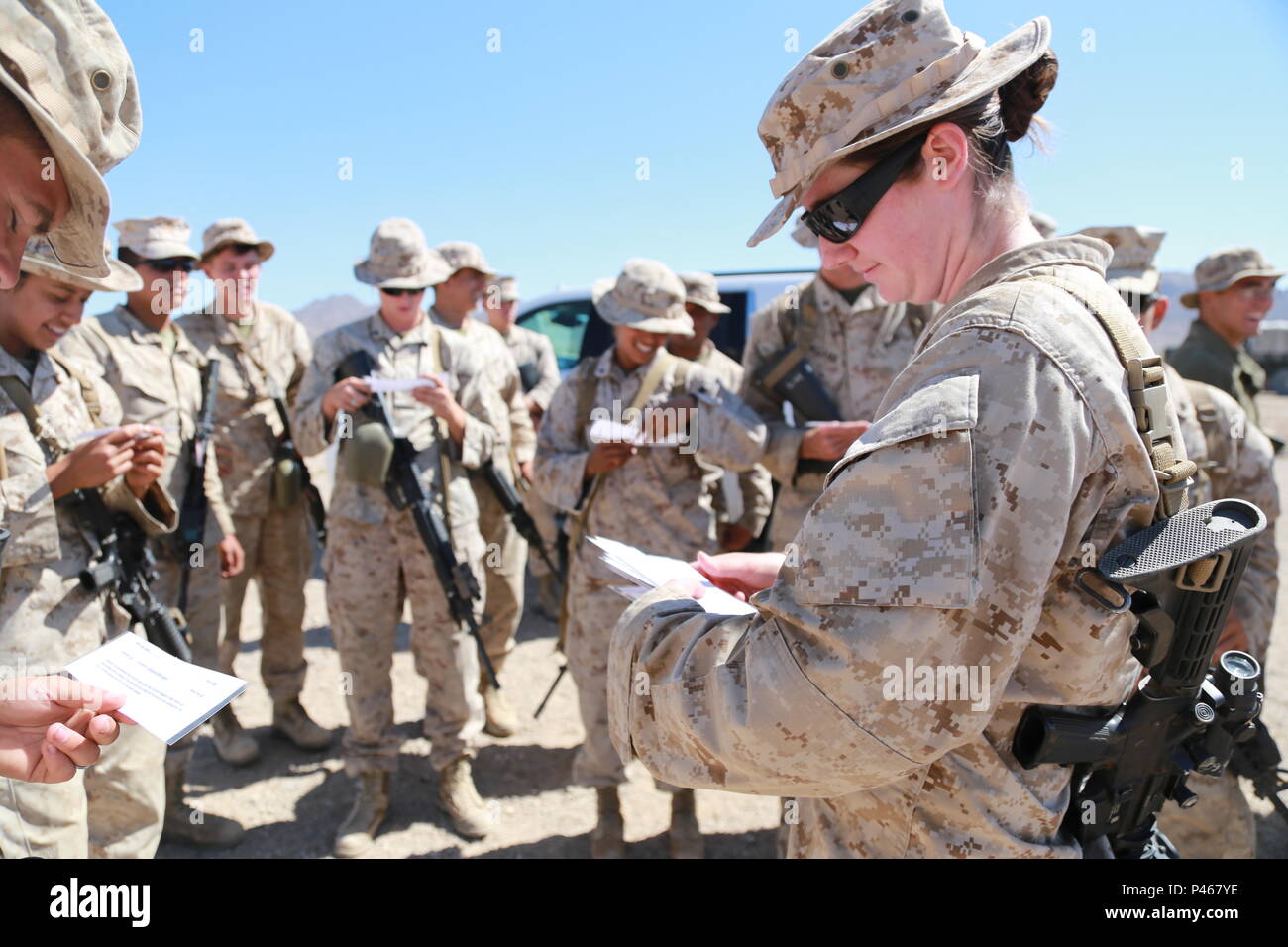 First Lt. Alyssa Renosto disributes papers with designated roles and a scenario for an evacuation control center operations rehearsal during the 11th Marine Expeditionary Unit’s Combined Arms Exercise at Marine Corps Air Ground Combat Center Twentynine Palms, Calif., June 12, 2016. The MEU’s logistics element performs a variety of duties beyond supplying beans, bullets and band aids. Among its other capabilities, the logistics element can plan, brief and execute ECC missions. This consists of the processing and screening of individuals and other logistics functions associated with emergency no Stock Photo