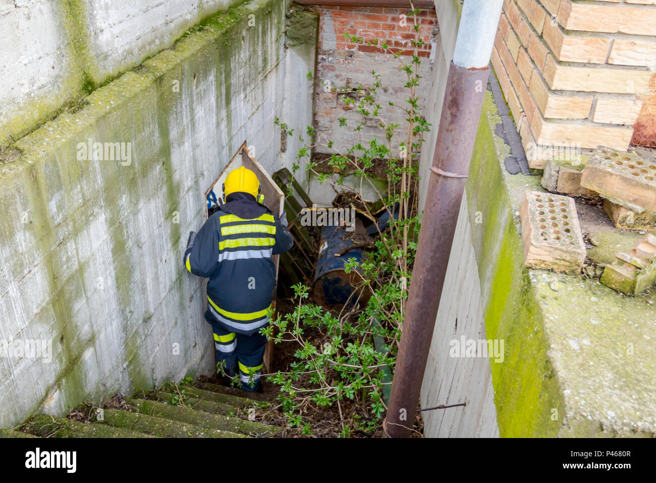 View from behind on firefighter in uniform is going down the staircase. Stock Photo