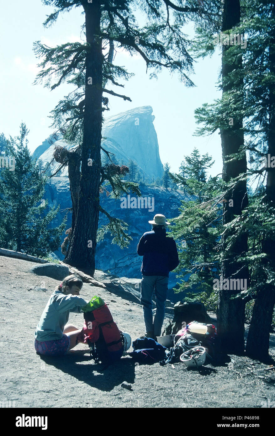 Hikers take a break on the trail to look at distant Half Dome, Yosemite National Park, California Stock Photo