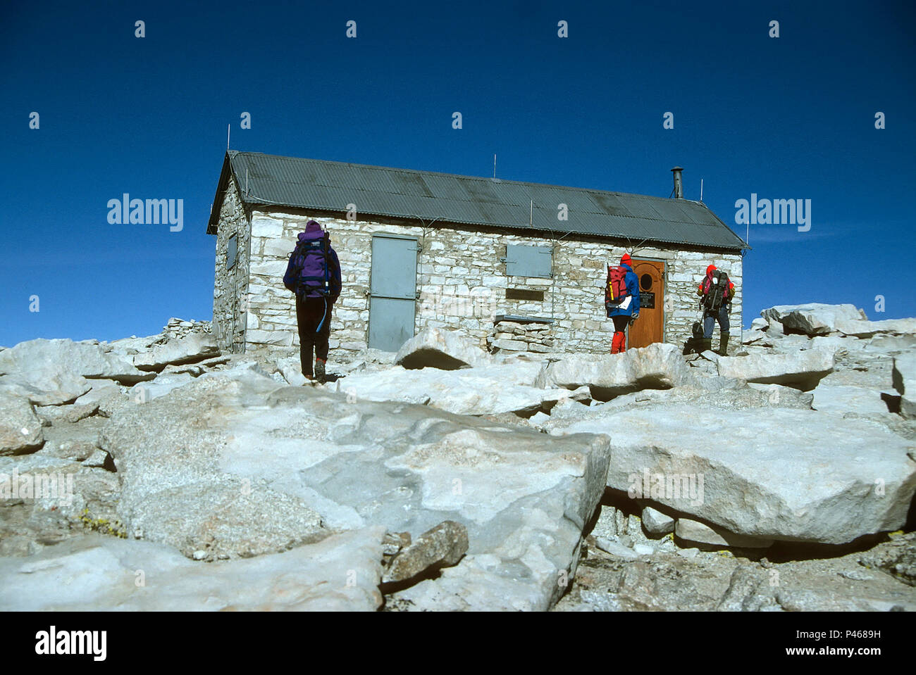 Hikers approach the storm shelter on the summit of Mount Whitney in the Sierra Nevada, California Stock Photo