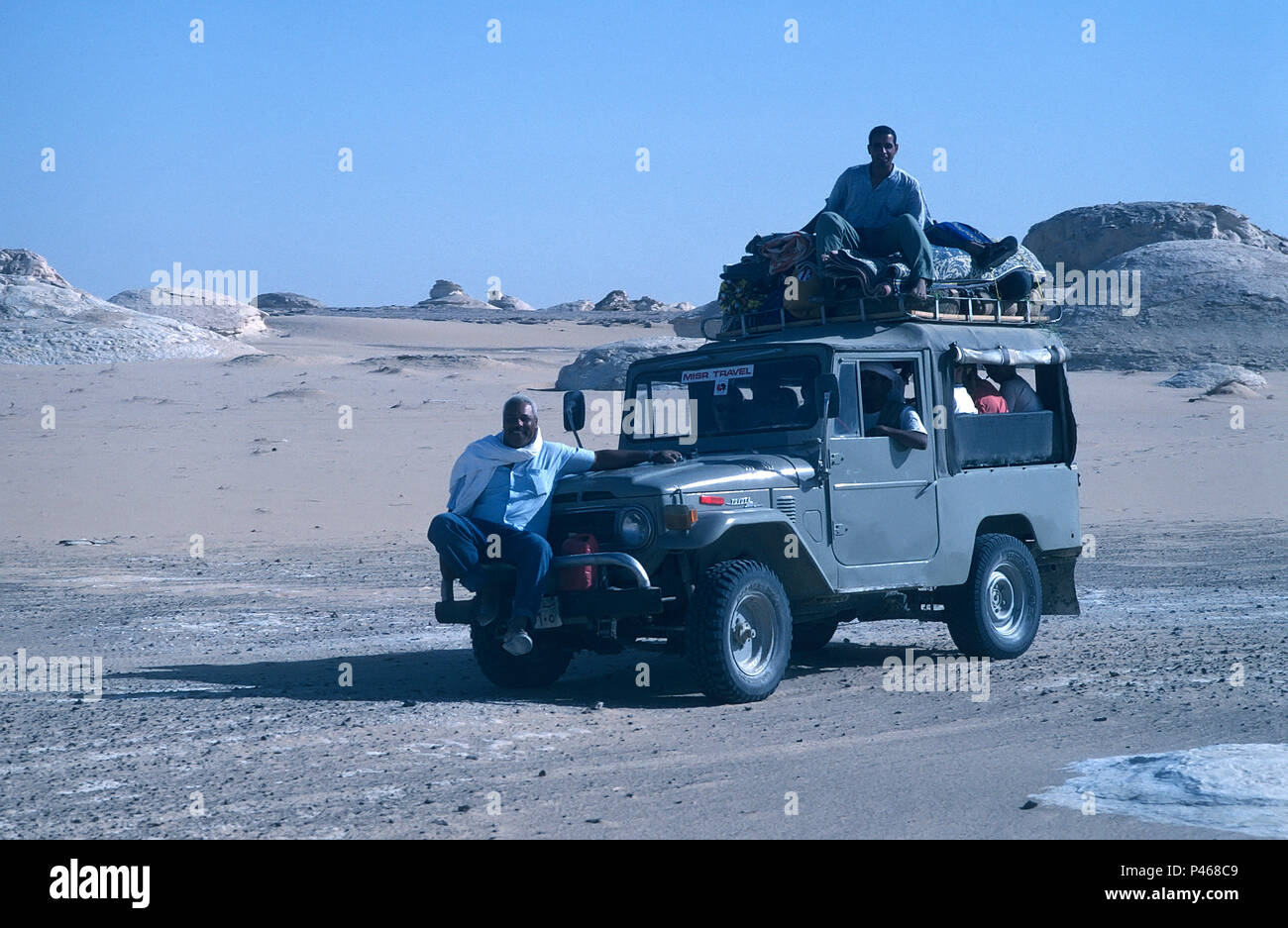 A tourist jeep in the Egyptian desert with the tour guide sat on the front bumper Stock Photo