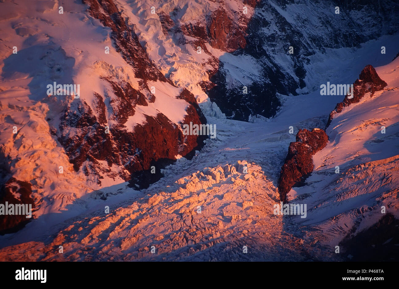 Alpenglow colours La Jonction and the Glacier des Bossons pink, with the Grands Mulets mountain hut visible on the rock island Stock Photo