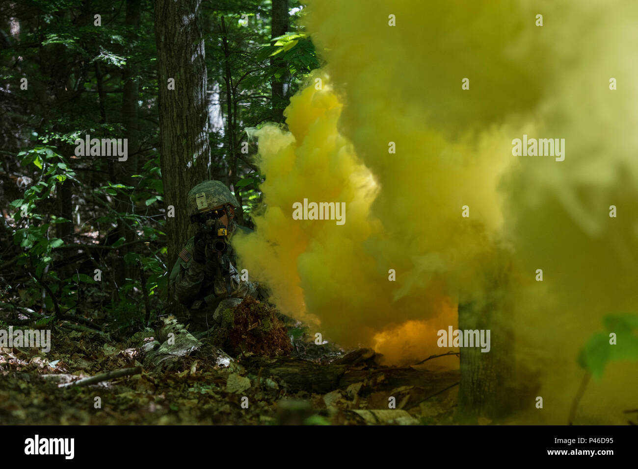 U.S. Army Pfc. Saul Hernandez, assigned to Alpha Company, 3rd Battalion, 172nd Infantry Regiment, 86th Infantry Brigade Combat Team (Mountain), Vermont National Guard, waits while smoke from a grenade creates cover, Camp Ethan Allen Training Site, Jericho, Vt., June 15, 2016. Hernandez is running through an assault lane as part of a buddy-team exercise, during the unit’s two-week annual training. (U.S. Air National Guard photo by Tech. Sgt. Sarah Mattison/Released) Stock Photo