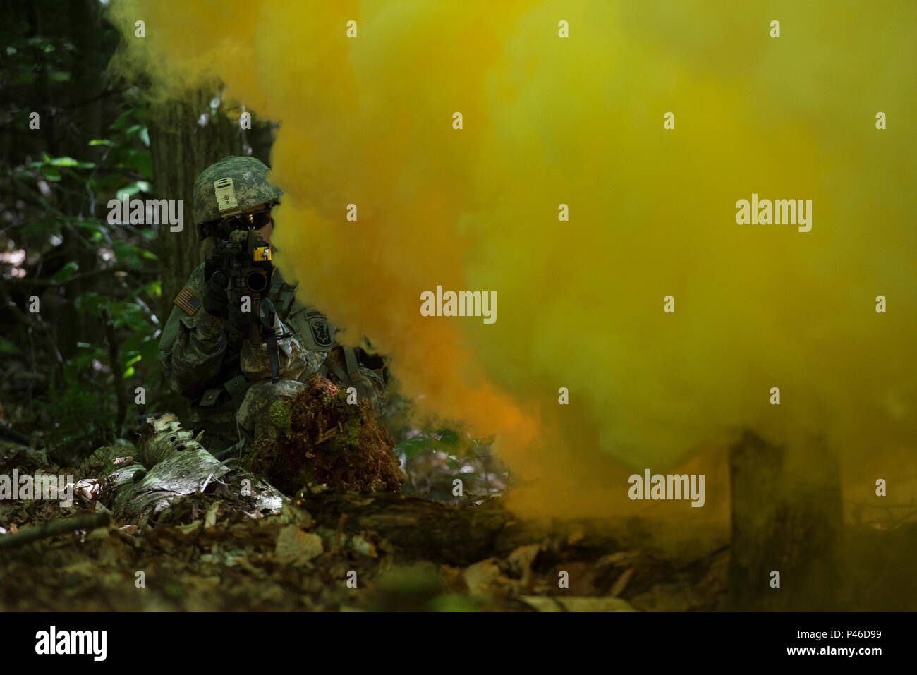 U.S. Army Pfc. Saul Hernandez, assigned to Alpha Company, 3rd Battalion, 172nd Infantry Regiment, 86th Infantry Brigade Combat Team (Mountain), Vermont National Guard, waits while smoke from a grenade creates cover, Camp Ethan Allen Training Site, Jericho, Vt., June 15, 2016. Hernandez is running through an assault lane as part of a buddy-team exercise, during the unit’s two-week annual training. (U.S. Air National Guard photo by Tech. Sgt. Sarah Mattison/Released) Stock Photo