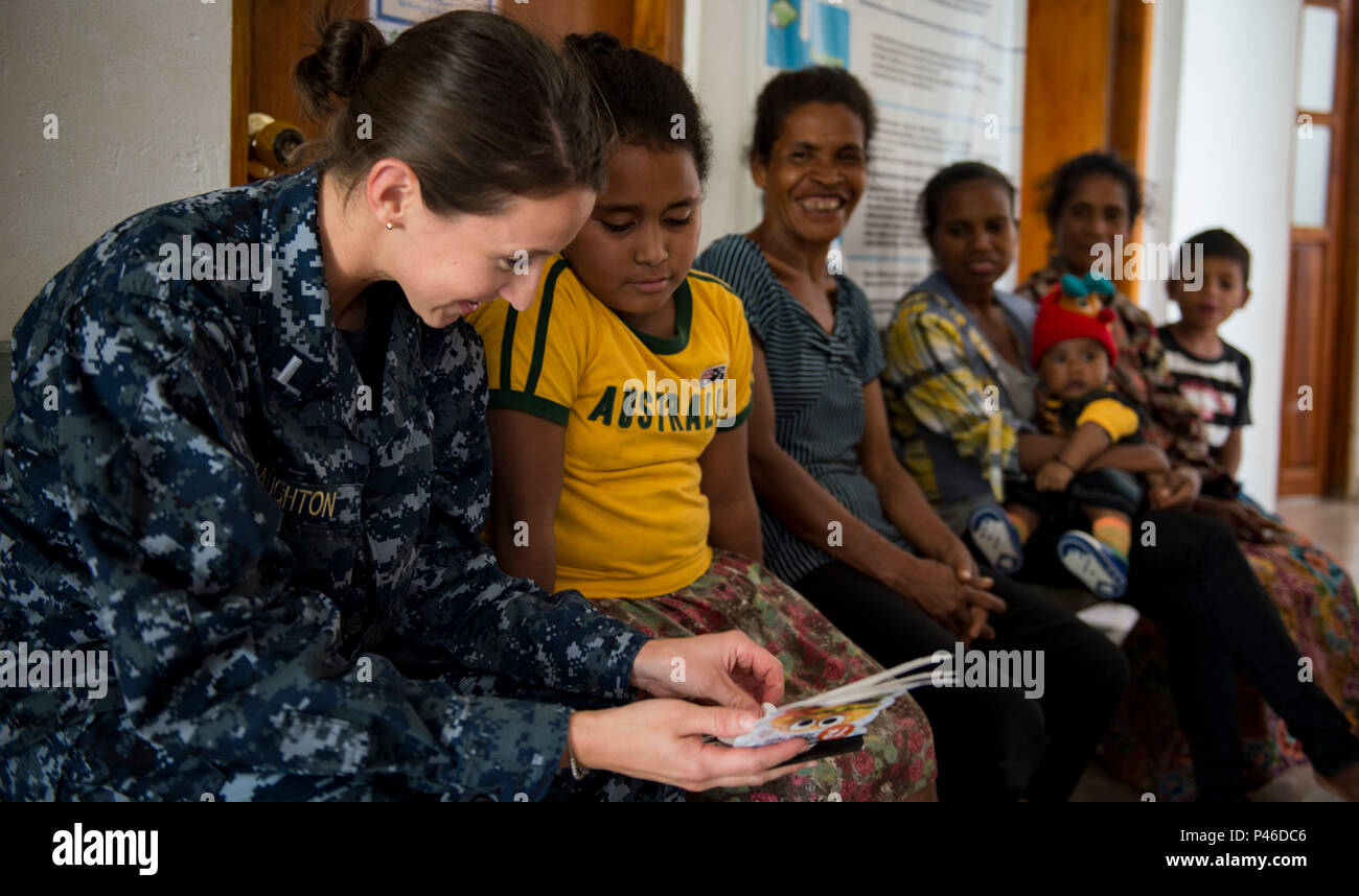160613-N-QW941-547 DILI, Timor Leste (June 13, 2016) Lt. j.g. Shelby Naughton, a native of Allentown, Pennsylvania, assigned to hospital ship USNS Mercy (T-AH 19) reads a book to a Timorese child at Gleno Community Health Center during a Pacific Partnership 2016 cooperative health engagement. This year marks the sixth time the mission visited Timor Leste since its first visit in 2006. Medical, engineering and various other personnel embarked aboard Mercy are working side-by-side with partner nation counterparts, exchanging ideas, building best practices and relationships to ensure preparedness Stock Photo