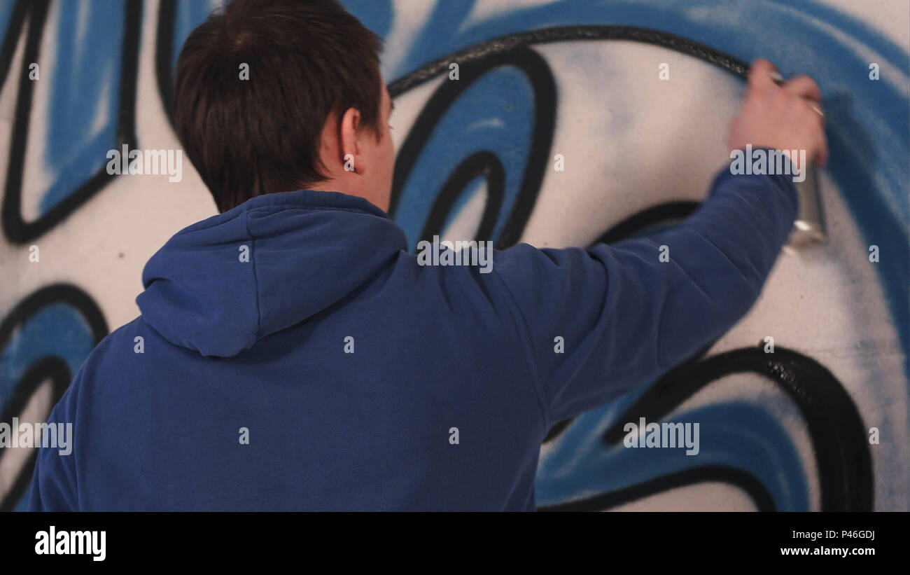 Male artist drawing graffiti on a wall with a spray can Stock Photo - Alamy