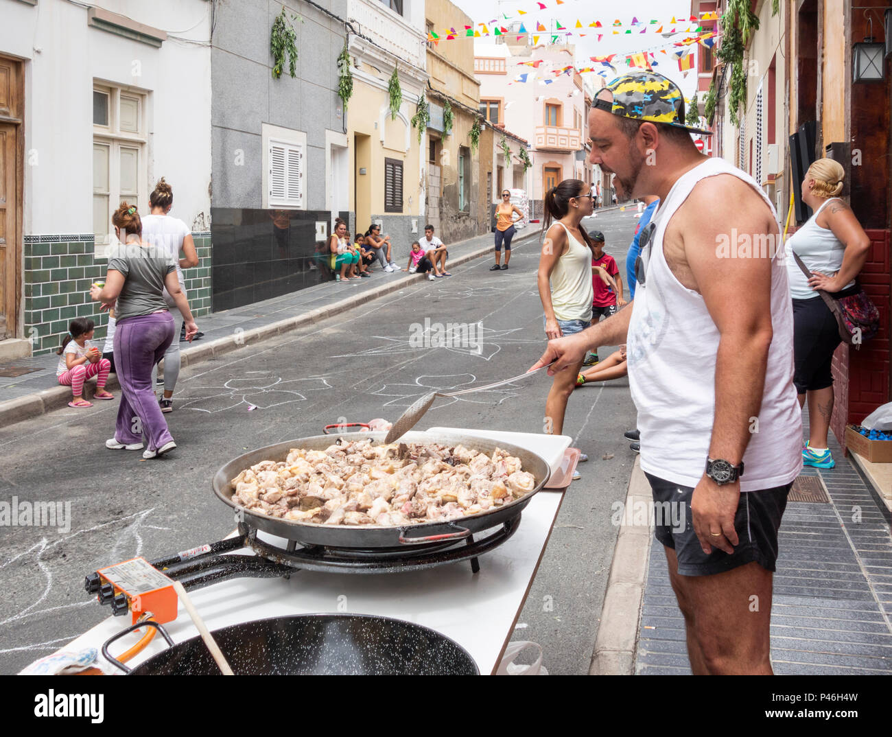 Spanish man preparing Paella in street ahead of Fiesta del Carmen procession. La Isleta, Las Palmas, Gran Canaria, Canary Islands, Spain Stock Photo