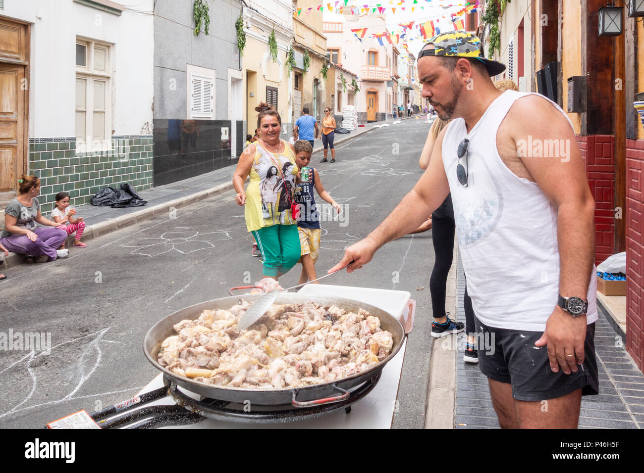Spanish man preparing Paella in street ahead of Fiesta del Carmen procession. La Isleta, Las Palmas, Gran Canaria, Canary Islands, Spain Stock Photo