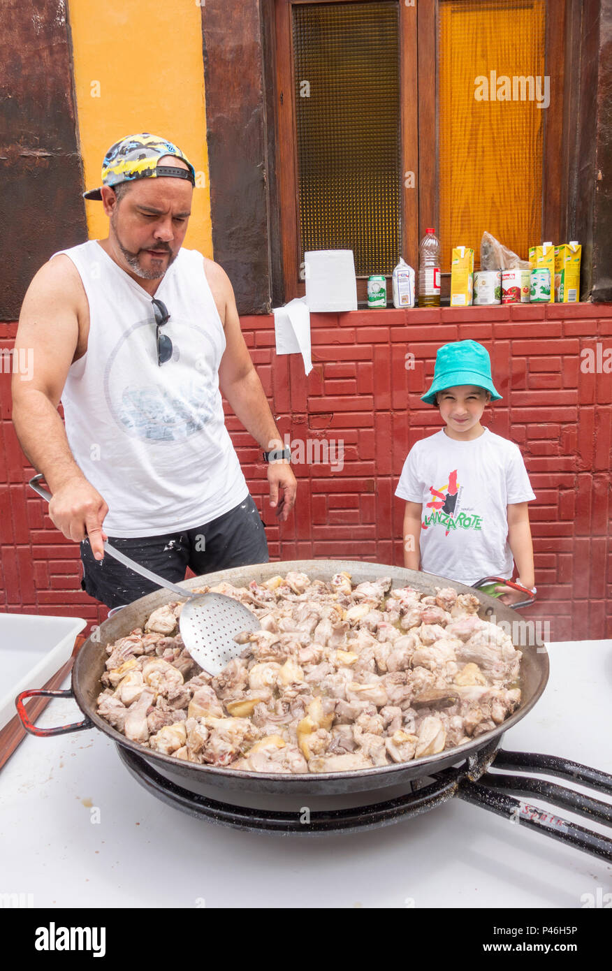 Chef hand cooking Spanish food meal on big pan on street market in