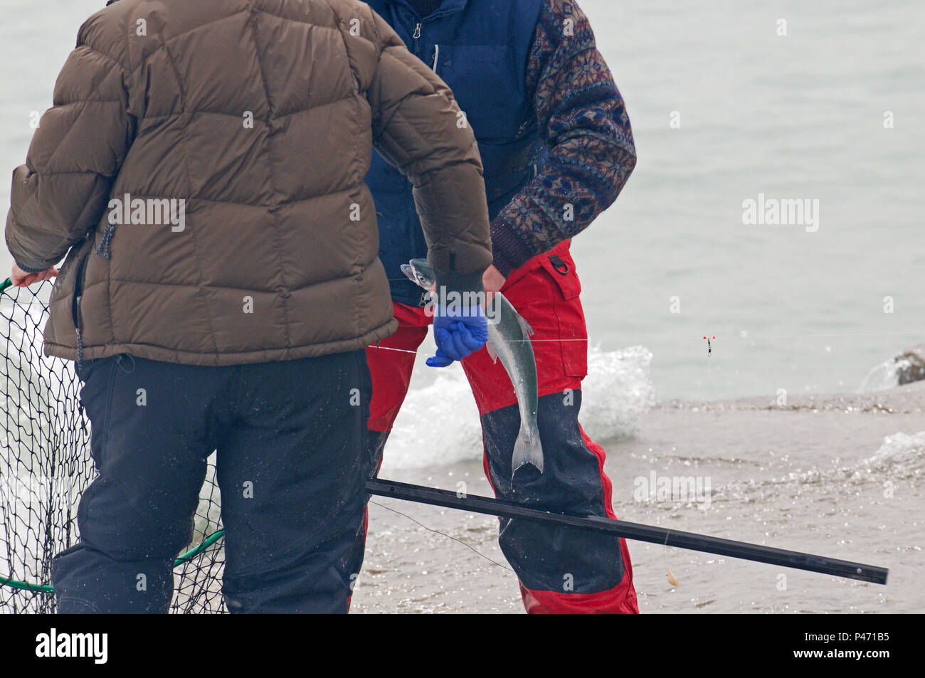 Men fishing for small spring coho salmon at the shore of lake Michigan