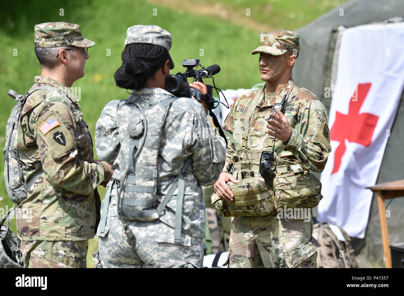 (From left to right), U.S. Army Staff Sgt. Mark Scovell and U.S. Army Sgt. Marline Duncon, both with 100th Mobile Public Affairs Detachment, interview U.S. Army Maj. James Falcon, a surgeon with the 1st Brigade Combat Team, 82nd Airborne Division, during Exercise Swift Response 16, June 16, 2016 in Hohenfels, Germany. Exercise Swift Response is one of the premier military crisis response training events for multi-national airborne forces in the world. The exercise is designed to enhance the readiness of the combat core of the U.S. Global Response Force - currently the 82nd Airborne Division's  Stock Photo