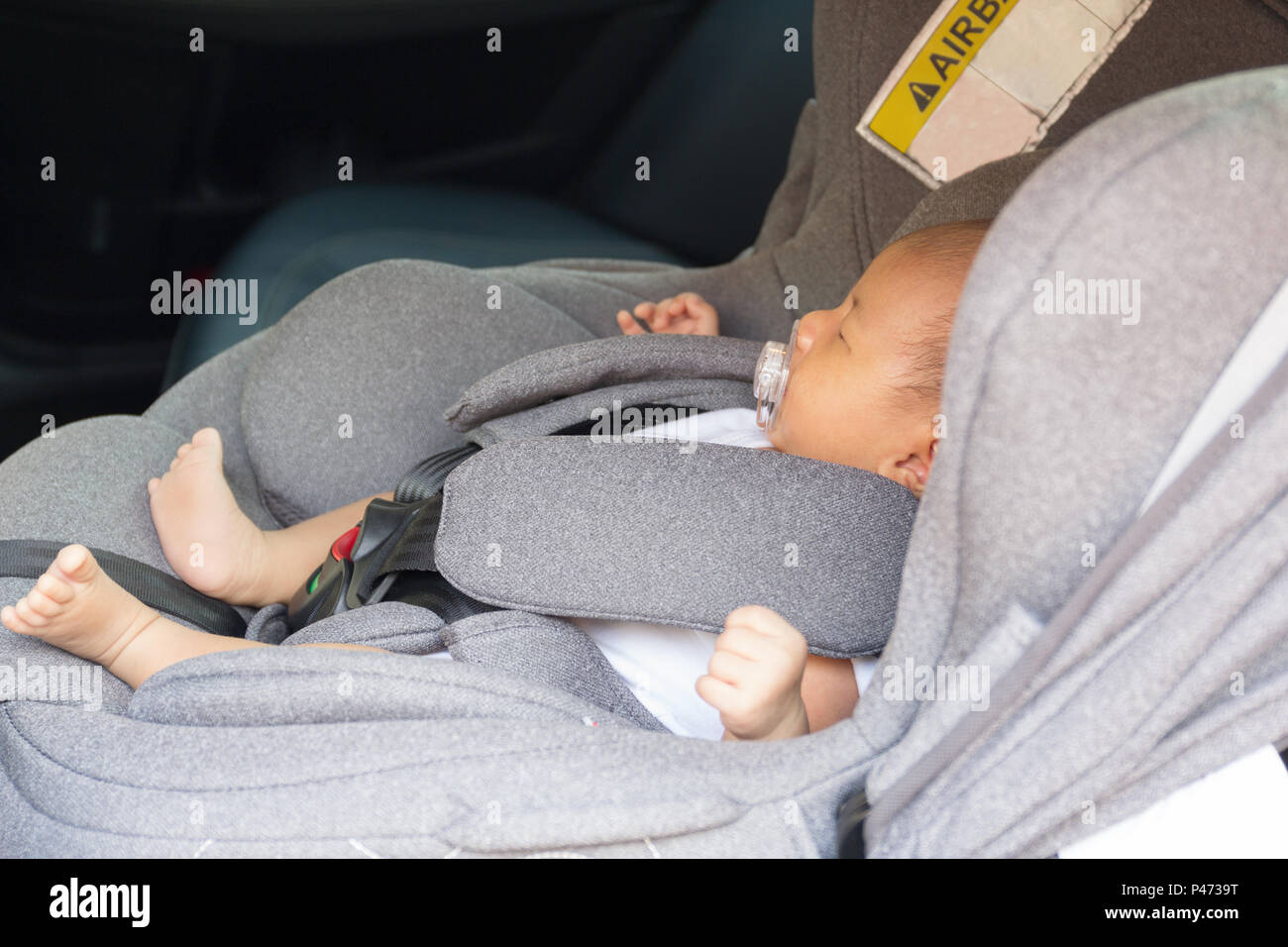 Asian cute newborn baby sleeping in modern car seat. Child new born