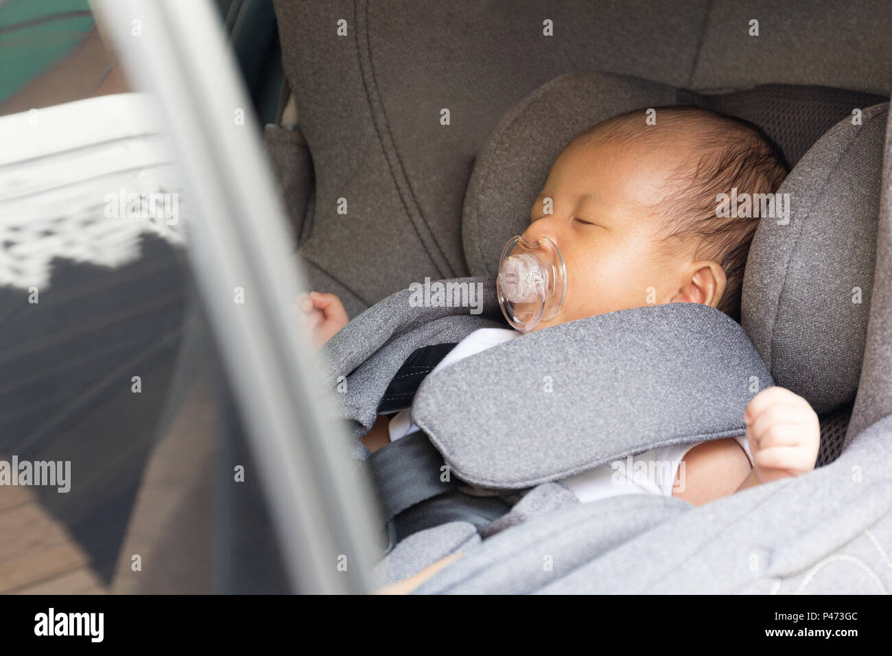 Asian cute newborn baby sleeping in modern car seat. Child new born