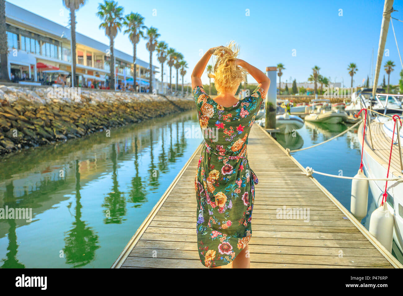 Tourism in Portugal. Lifestyle female tourist on wooden jetty at Marina de Lagos on Algarve coast, Portugal, Europe. Caucasian woman looking at the Bay of Lagos in summer holidays. Stock Photo