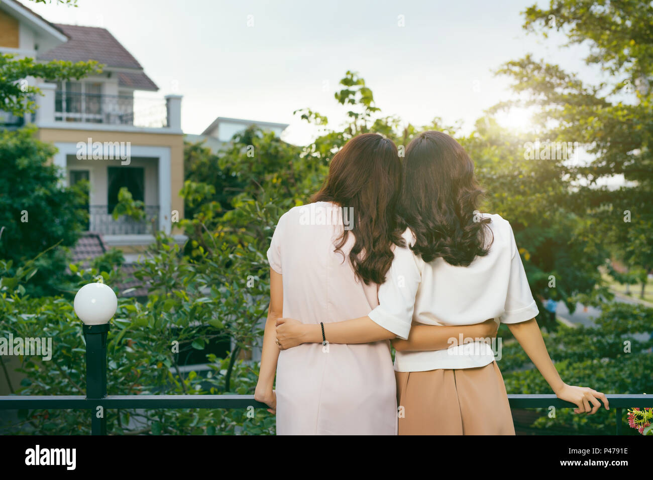 Outdoor fashion portrait of best girl friends posing back and hugs, both wearing stylish trendy hipster retro dresses. Enjoy their friendship and grea Stock Photo