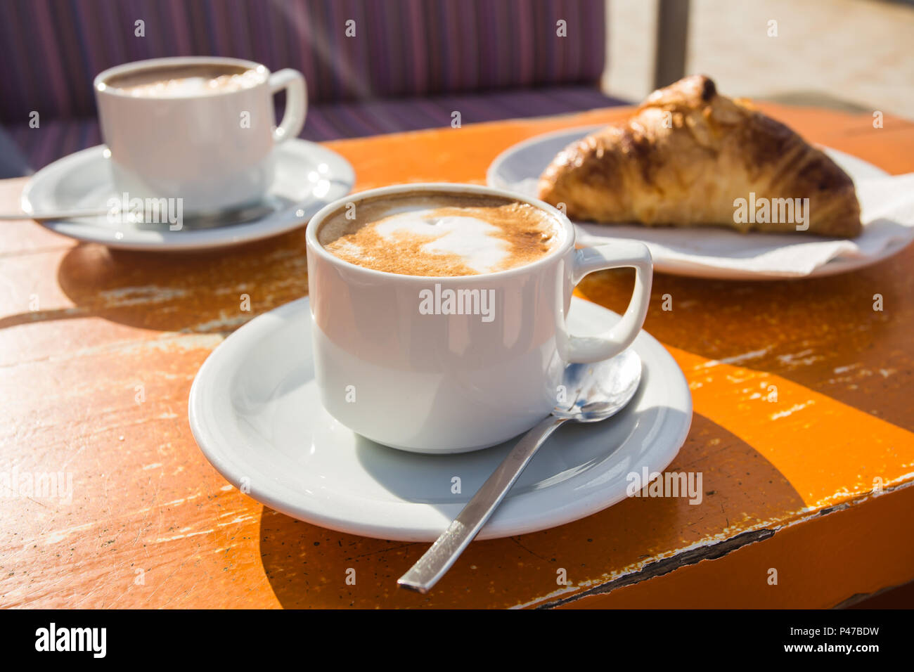 Two cups of invigorating cappuccino and a croissant for breakfast Stock Photo