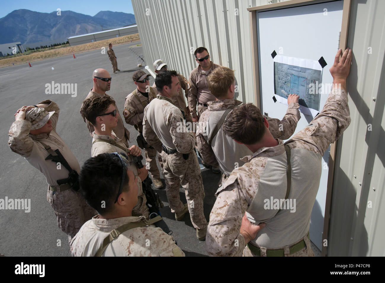 Marines and policemen review a map of their area of operations for a simulated urban raid during the 11th Marine Expeditionary Unit’s Realistic Urban Training near Minden, NV, June 18, 2016. RUT helps prepare the 11th MEU Marines for their upcoming deployment, enhancing Marines' combat skills in a simulated urban environment similar to those they may find during combat missions. The Marines are with the Maritime Raid Force, 11th MEU, and the policemen are with the Reno Police Department Special Weapons and Tactics team (U.S. Marine Corps photo by Sgt. Xzavior T. McNeal/Released) Stock Photo