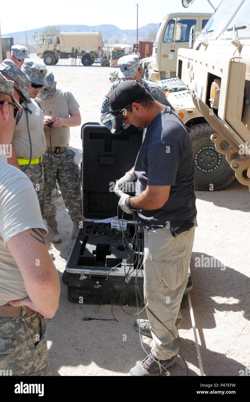 Larry Bussell, a pyro technician for Raytheon, shows soldiers assigned to the 626th Maintenance Company how to install a Multiple Integrated Laser Engagement System (MILES) on to a Palletized Loading System during the Reception Staging Onward Movement phase of the 16-07 National Training Center rotation at Fort Irwin, California on June 6, 2016.  MILES is a training device that provides tactical engagement simulation for direct fire force-on-force training using eye safe laser 'bullets'.  The NTC is a training facility designed to simulate real-life combat scenarios testing warriors’ readiness Stock Photo