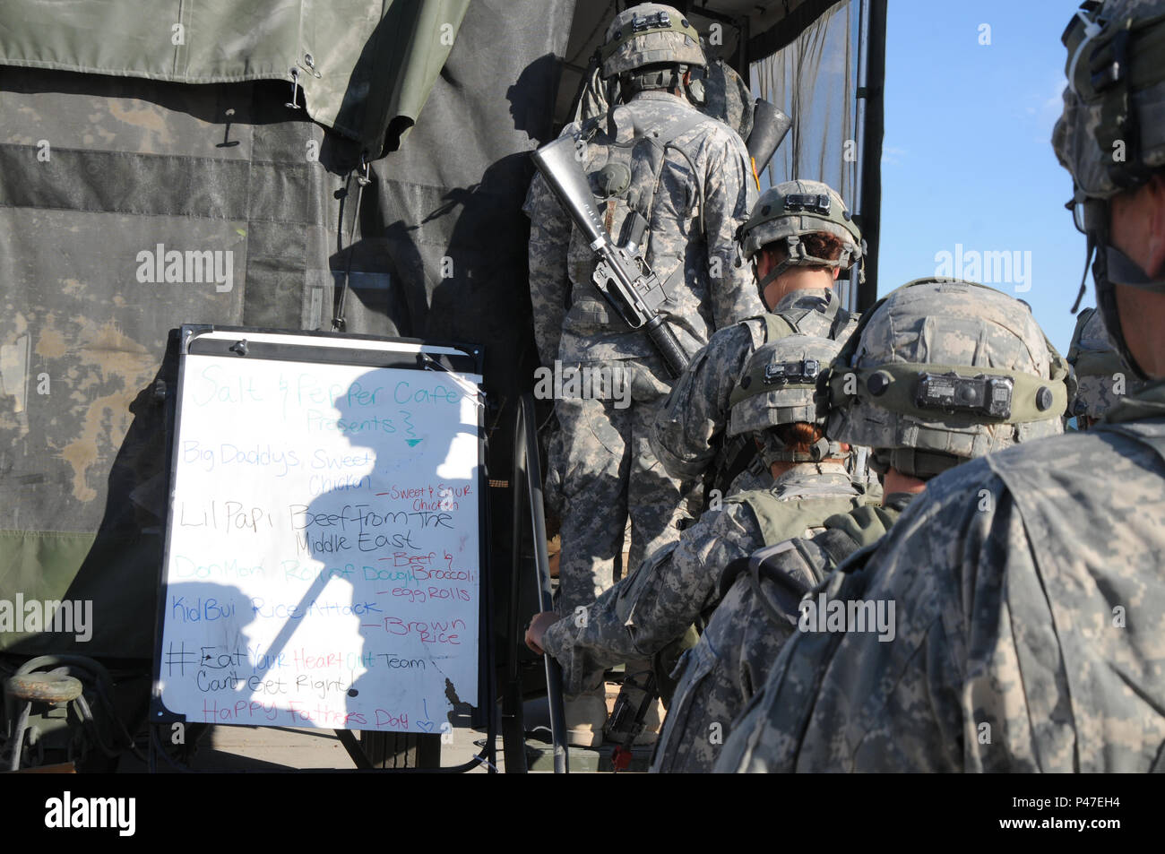 North Carolina Army National Guard soldiers anxiously wait in line outside the Mobile Kitchen Trailers (Salt and Pepper Café) for evening “chow” at the Logistics Support Area Forward Operating Base Santa Fe, Fort Irwin, California during the 16-07 National Training Center (NTC) rotation on June 19, 2016.  The MKT uses a four-man crew to set up and if doubled can serve over 500 meals per day.  The NTC is a training facility designed to simulate real-life combat scenarios testing warriors’ readiness utilizing their military occupational specialty in a high-up-tempo environment.  (U.S. Army Natio Stock Photo
