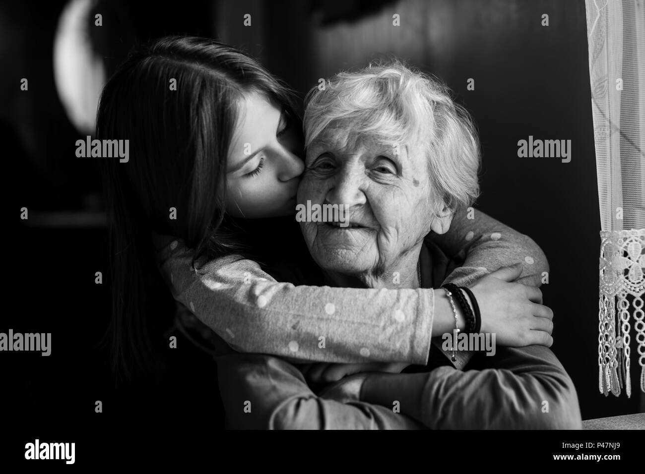 A little girl hugs her grandmother. Black and white photo. Stock Photo