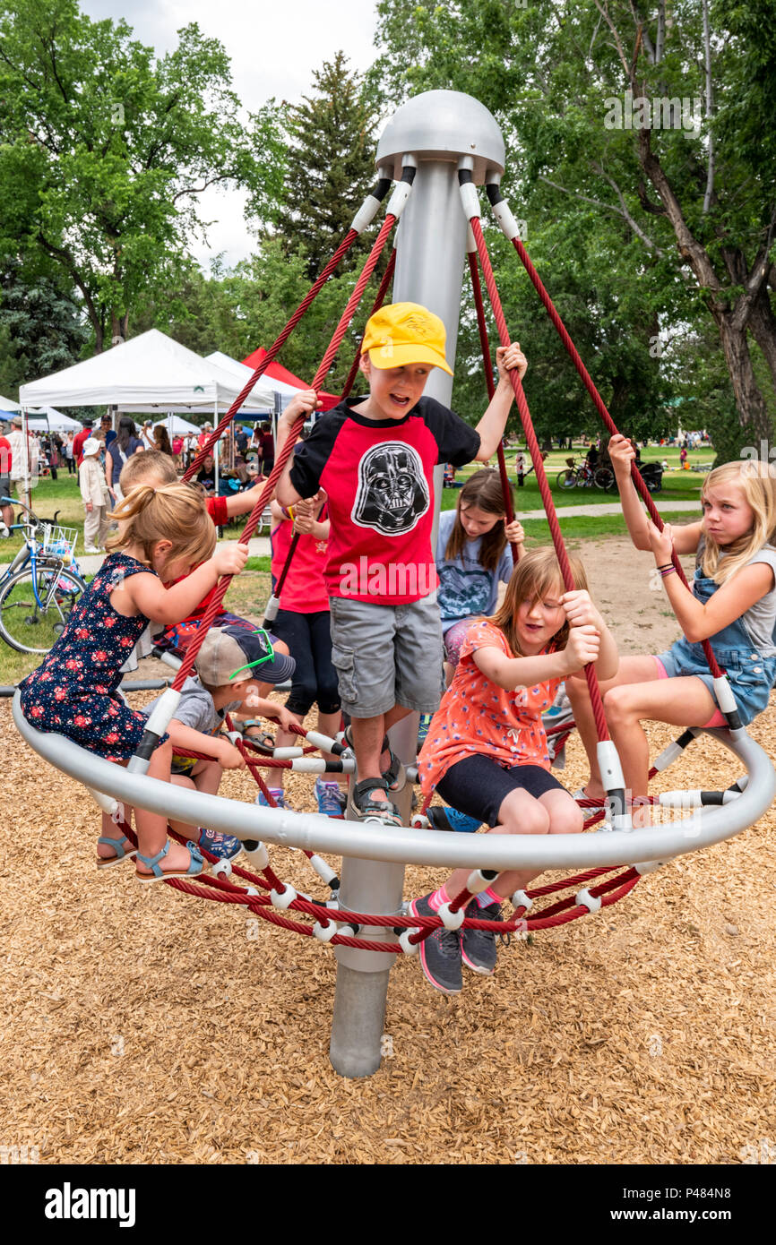 Young children spinning on playground merry-go-round; Salida; Colorado; USA Stock Photo