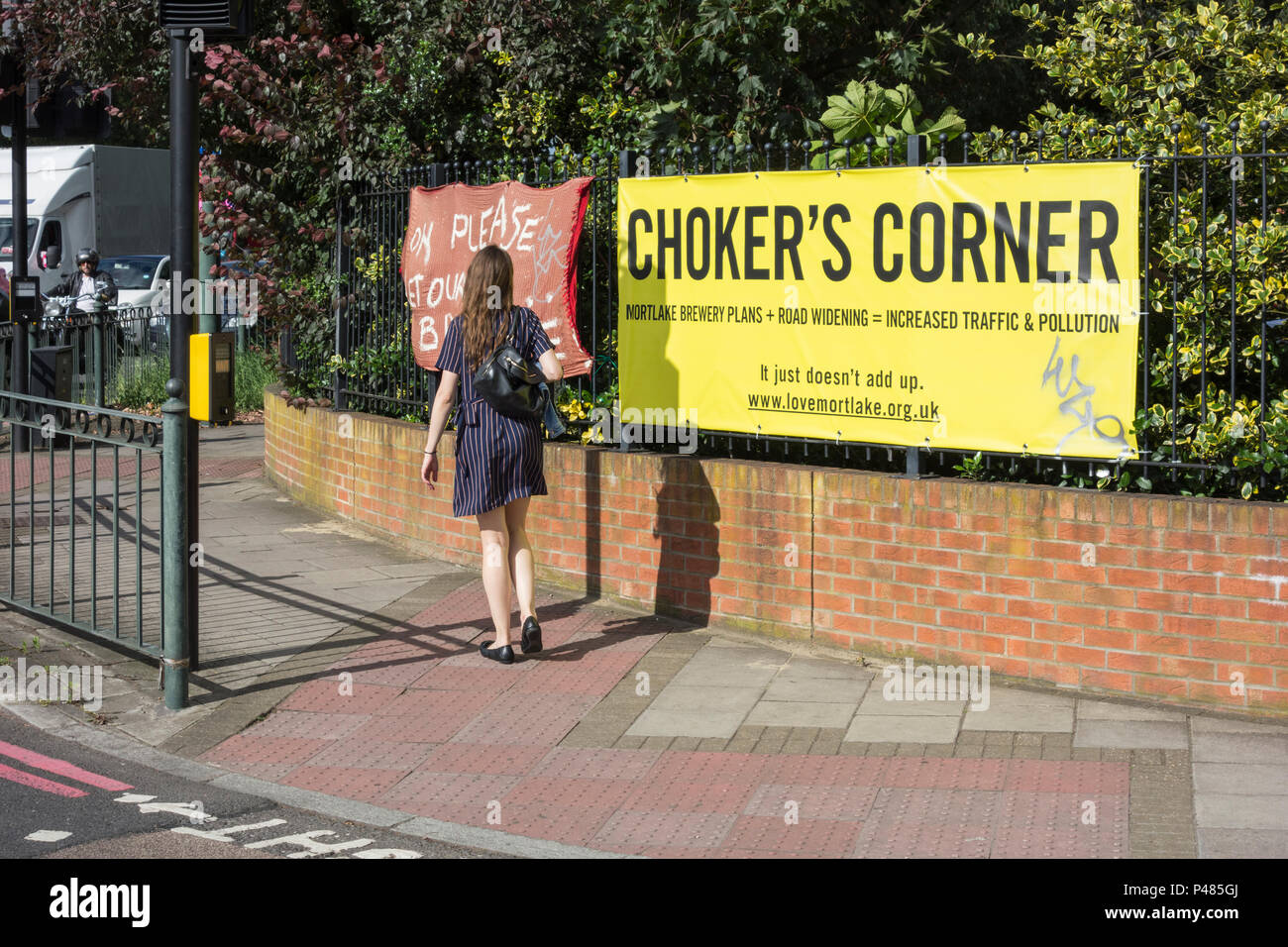 A woman crossing the road at Chalkers' Corner in front of Chertsey Court,  Mortlake, London, SW14, UK Stock Photo