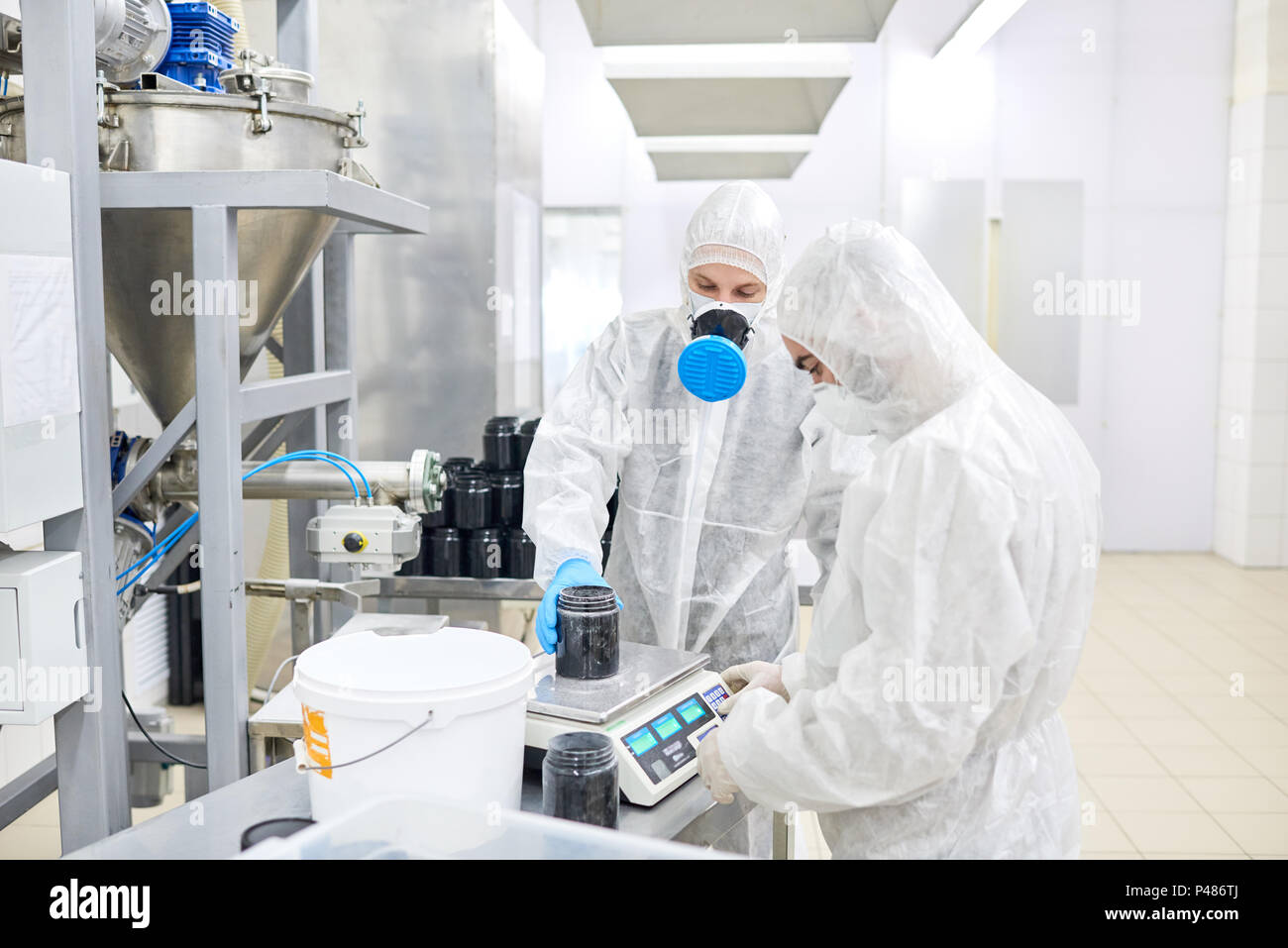 Factory workers weighing plastic container with product Stock Photo Alamy