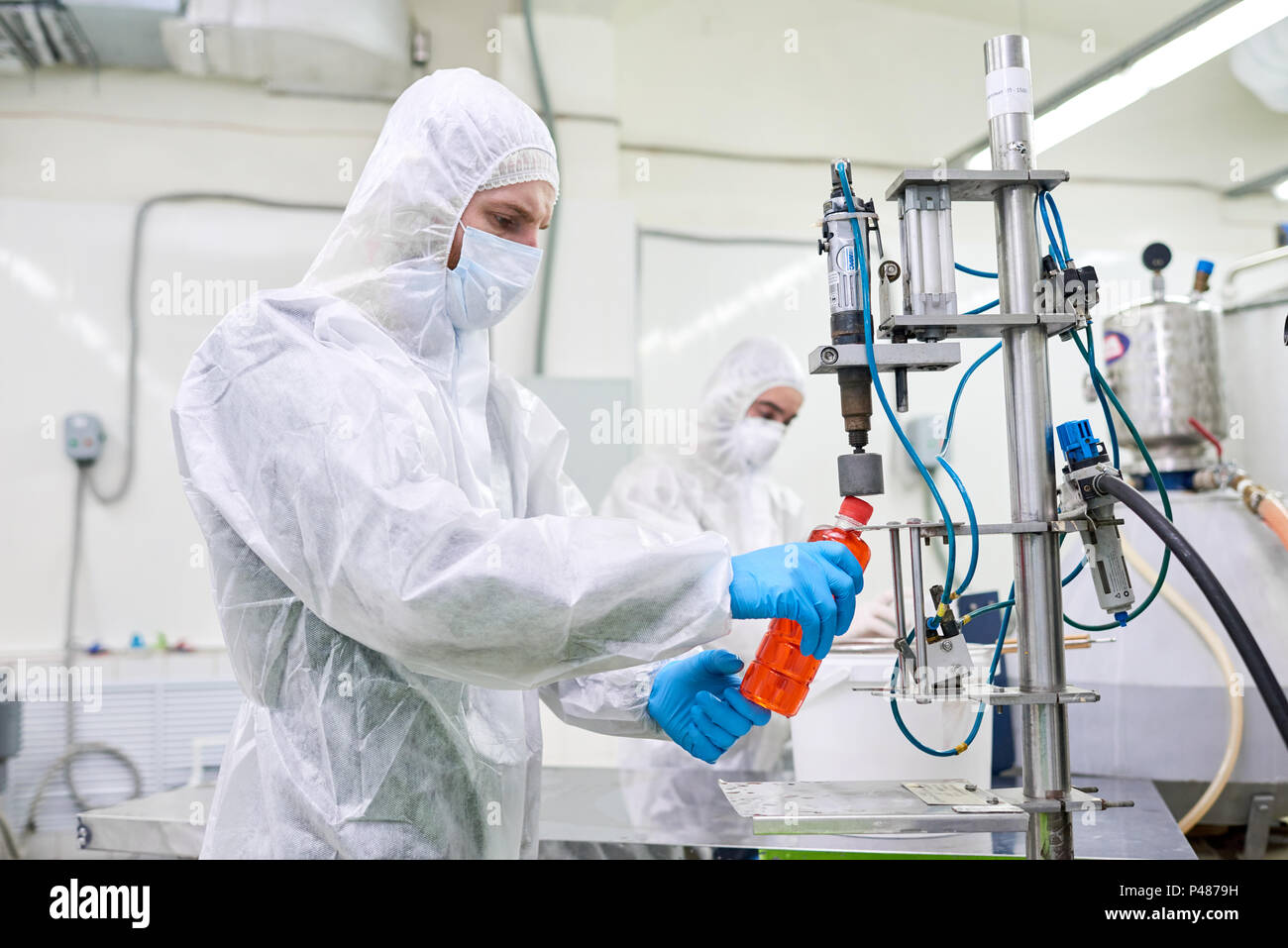 Factory worker closing bottle with sports drink Stock Photo