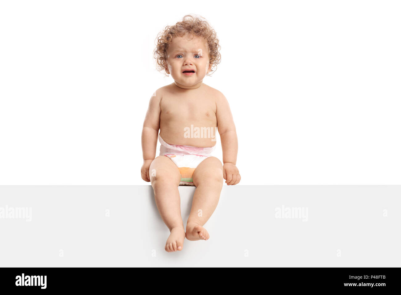 Baby boy sitting on a panel and crying isolated on white background Stock Photo