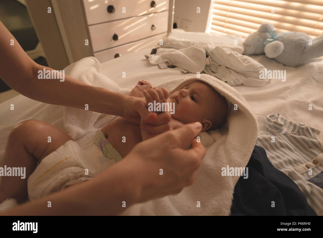 Cute baby lying on bed and mother playing with him on bed Stock Photo