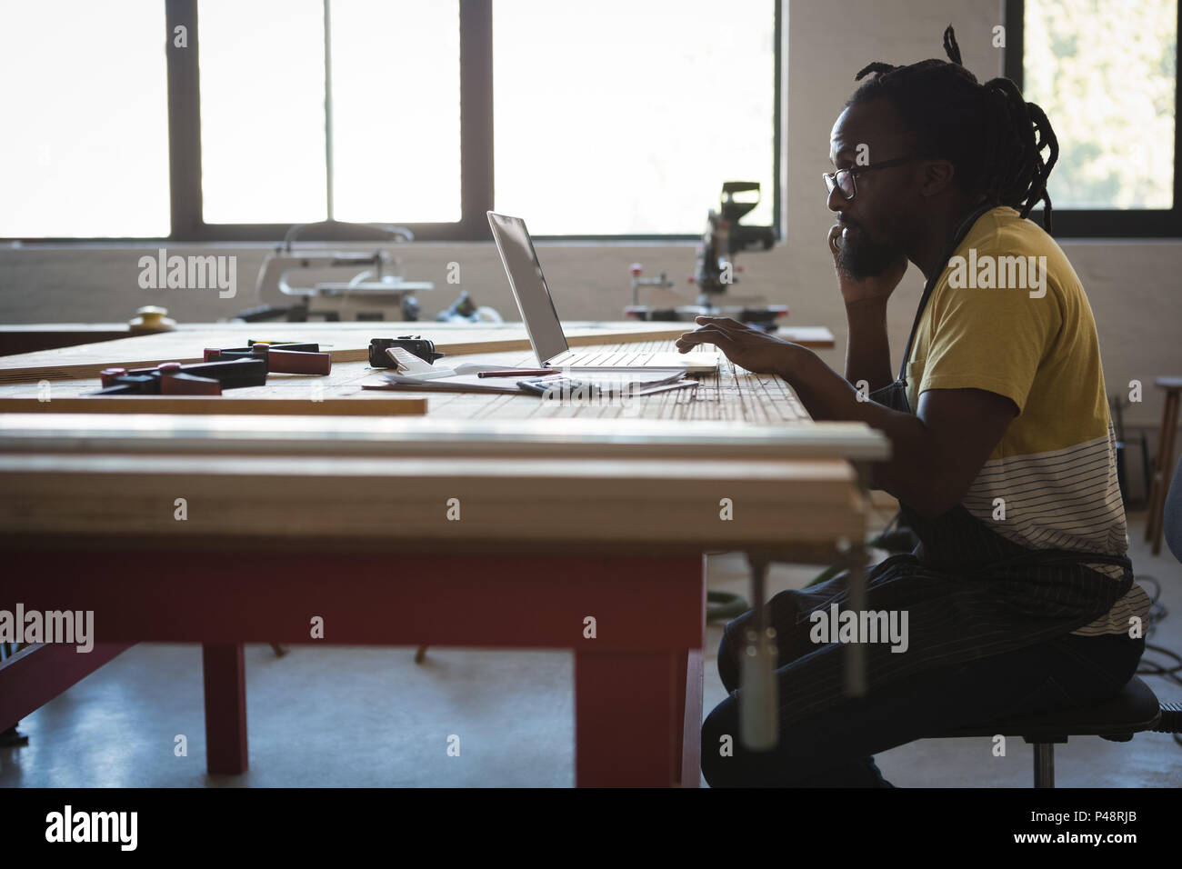 Carpenter talking on mobile phone while using laptop Stock Photo