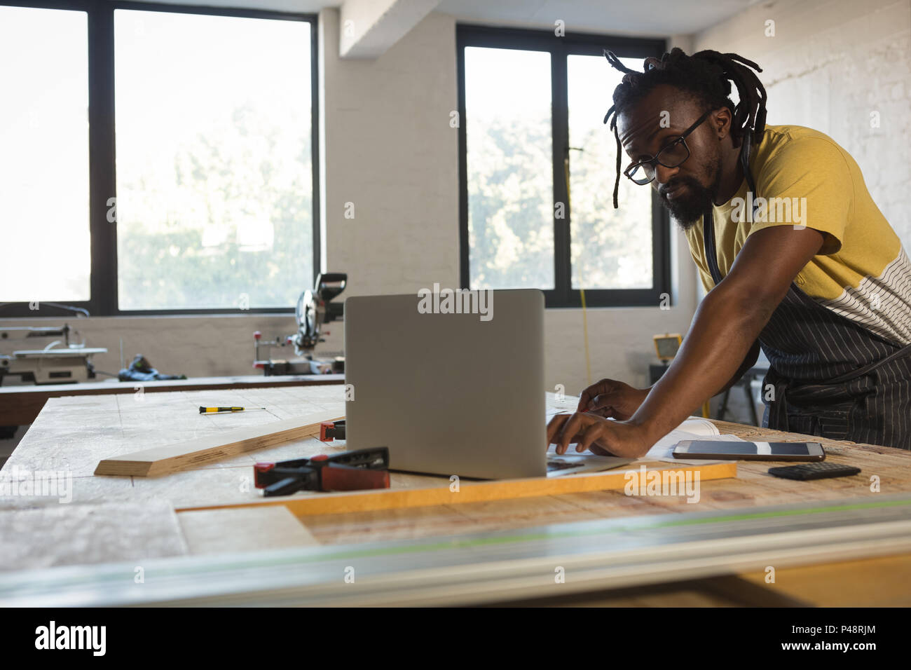 Carpenter using laptop at table Stock Photo