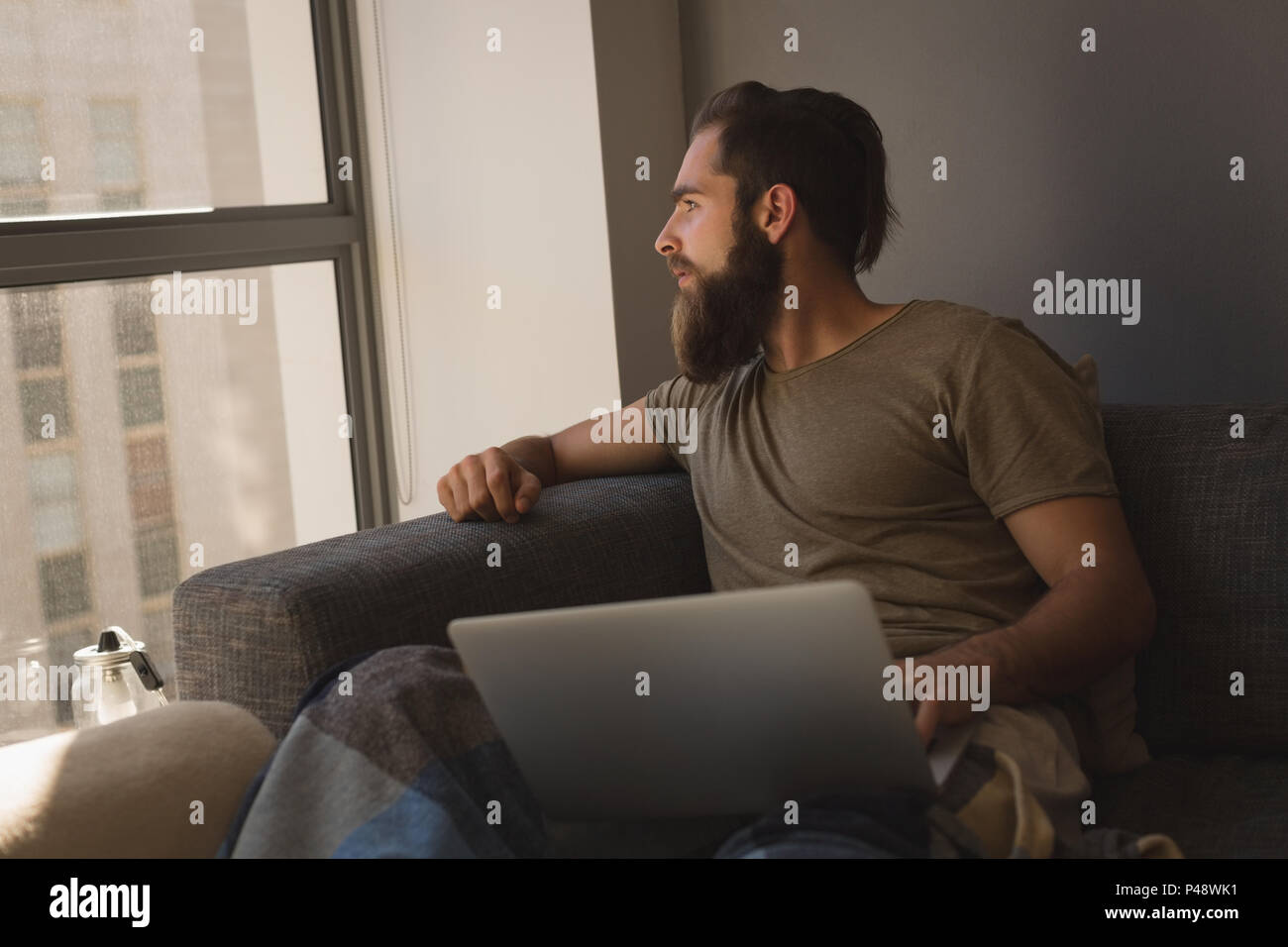 Man looking through window while using laptop Stock Photo